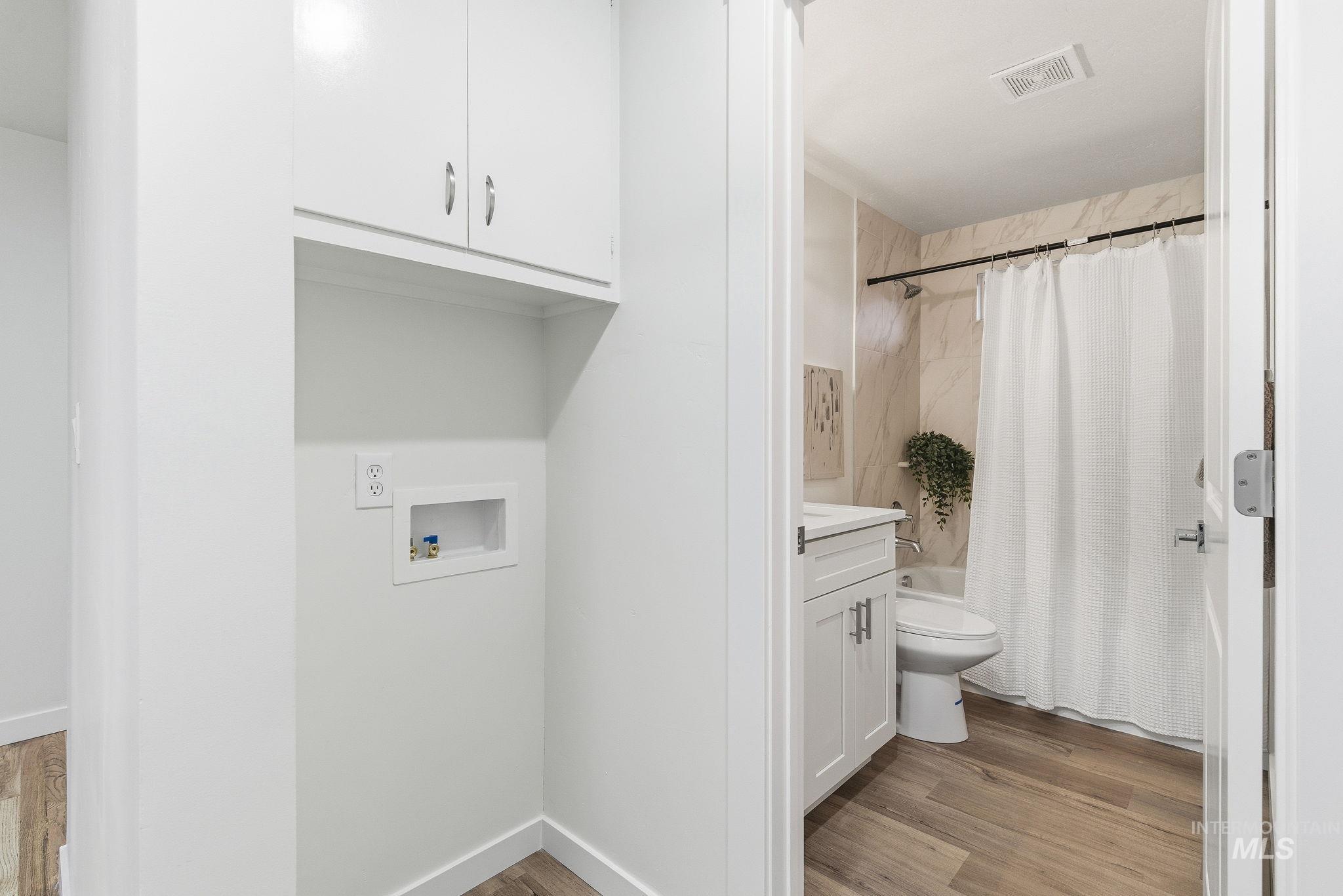 Laundry room featuring light wood-style flooring, washer hookup, and cabinet space