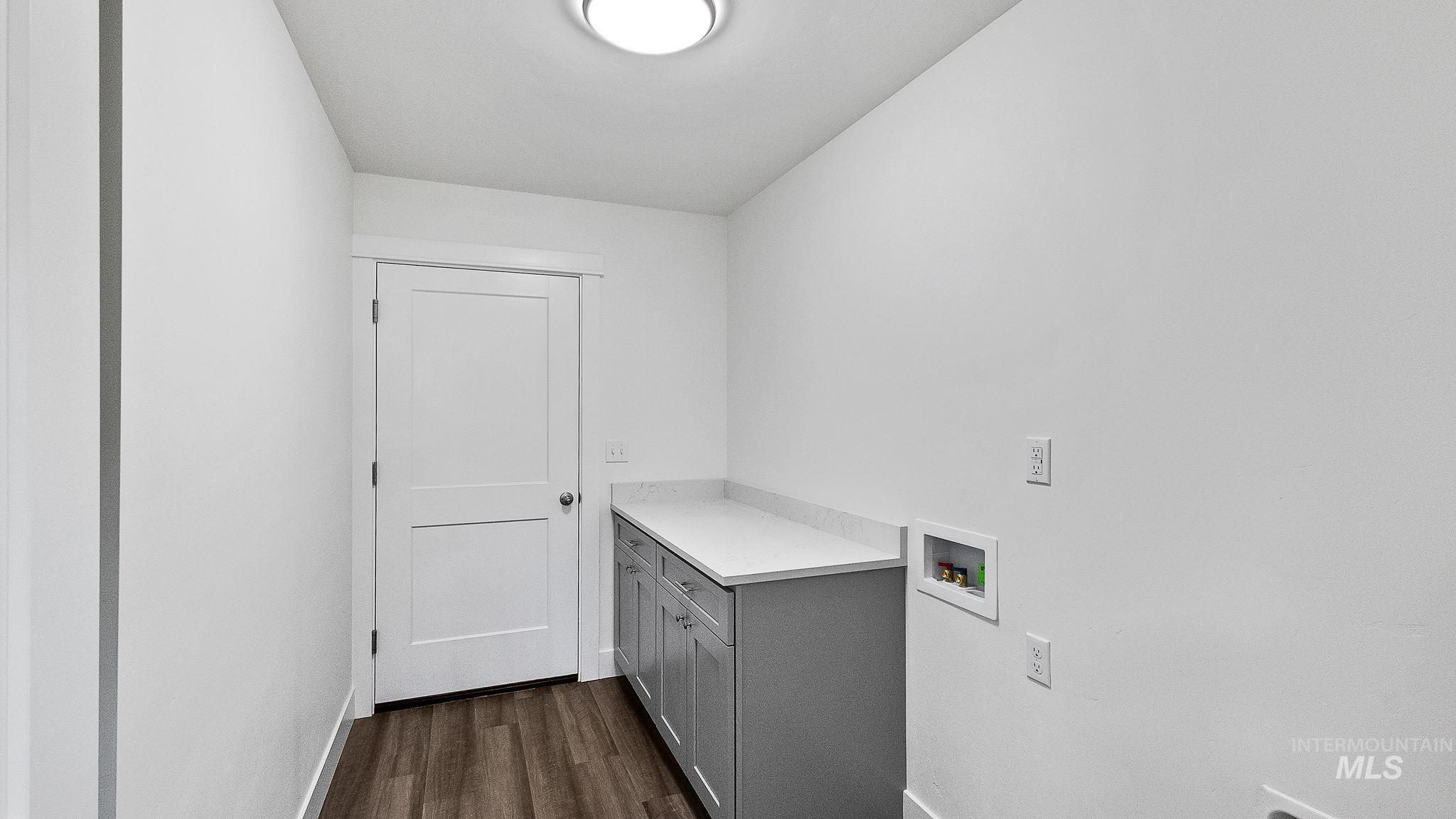 Laundry area featuring washer hookup, cabinet space, and dark wood-style flooring