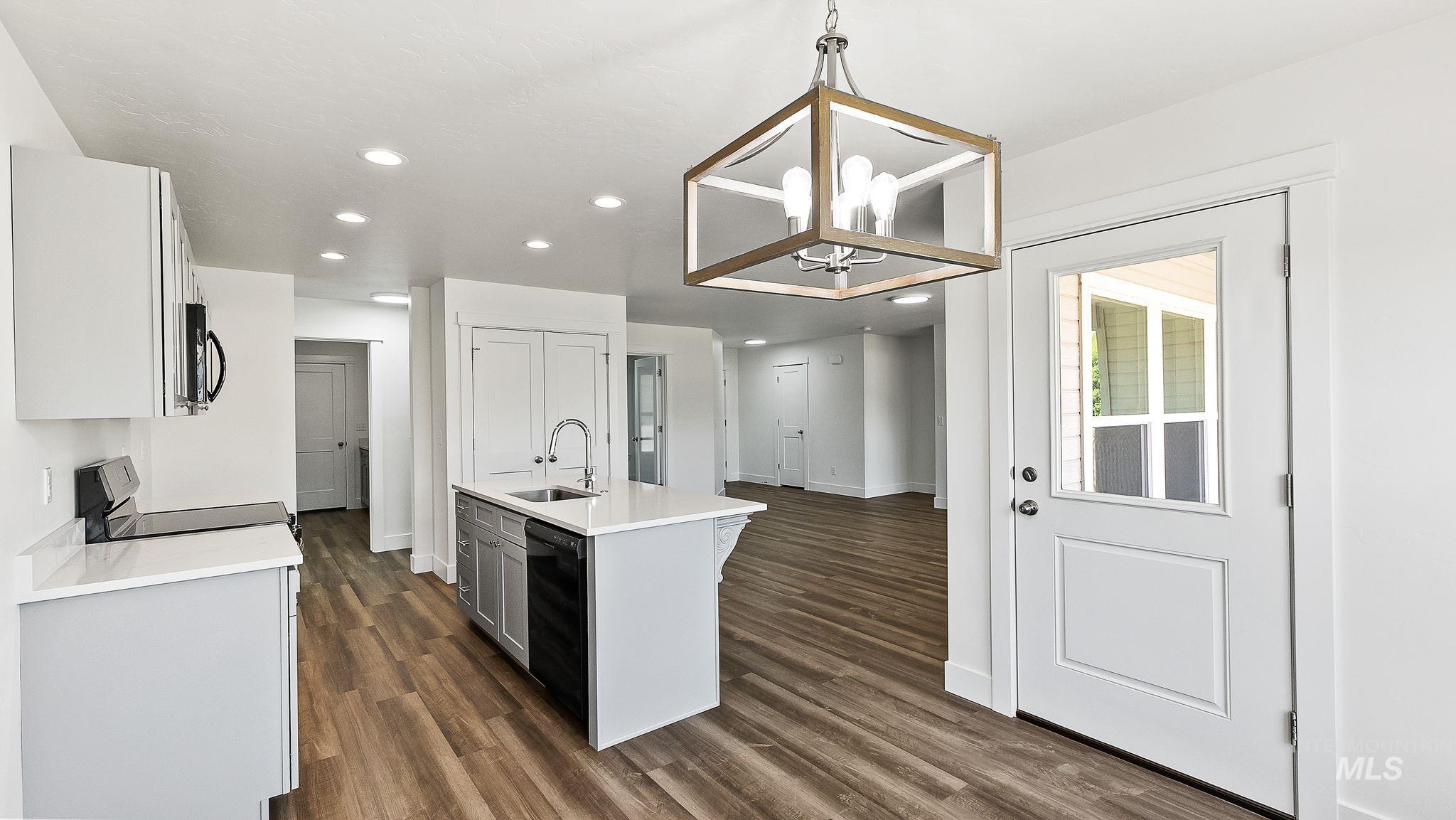 Kitchen featuring pendant lighting, recessed lighting, a center island with sink, light stone countertops, and dark wood-type flooring