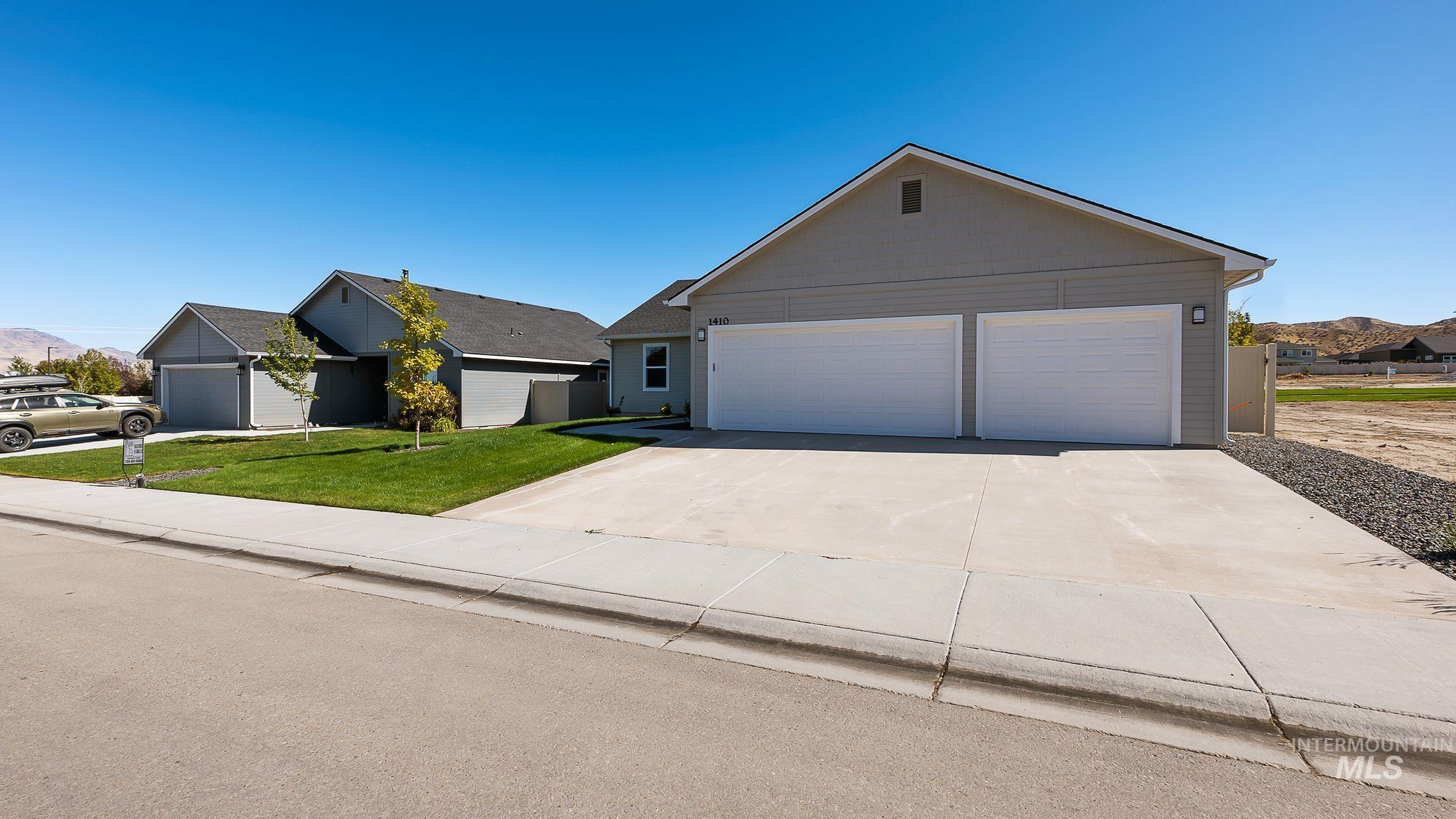 Ranch-style house featuring concrete driveway, a garage, a mountain view, and a front yard