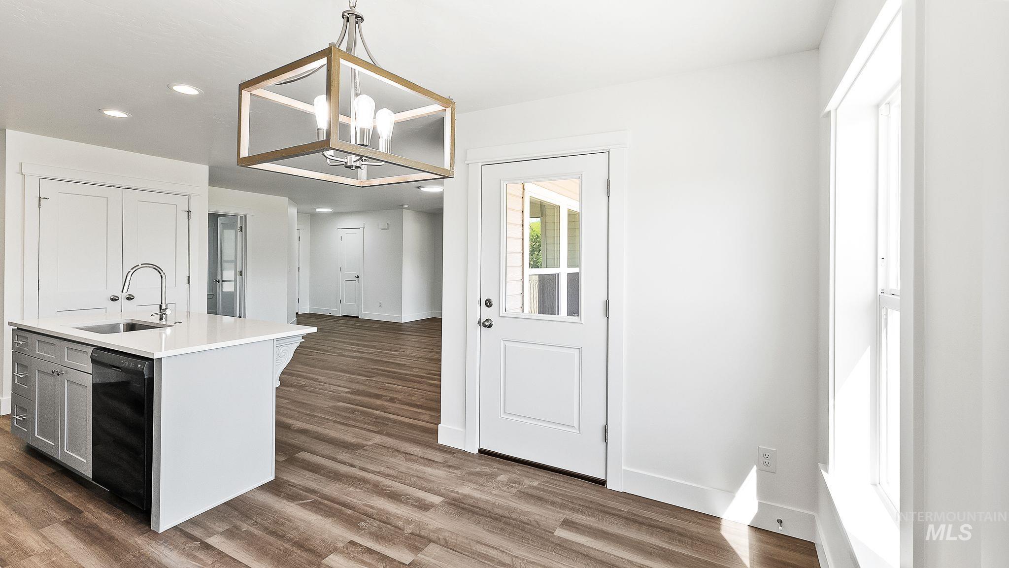 Kitchen with decorative light fixtures, recessed lighting, an island with sink, dark wood-style flooring, and gray cabinets