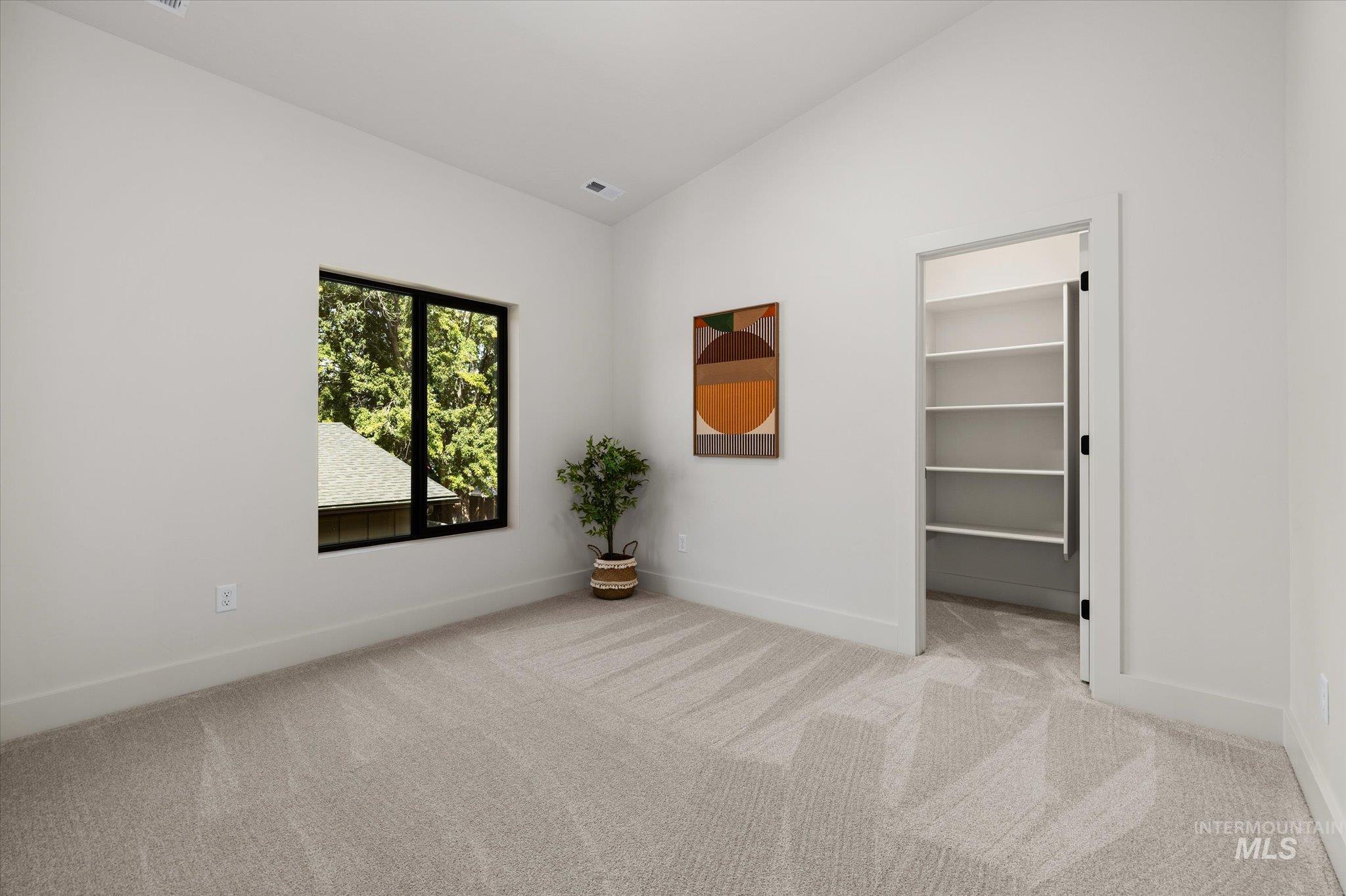 Carpeted spare room with lofted ceiling and baseboards