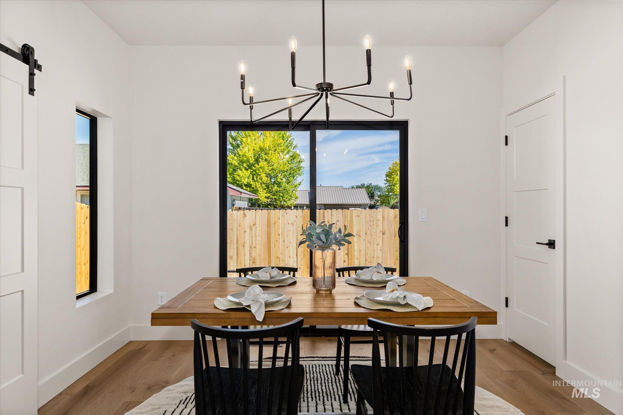 Dining space featuring a barn door, plenty of natural light, light wood-type flooring, and a chandelier
