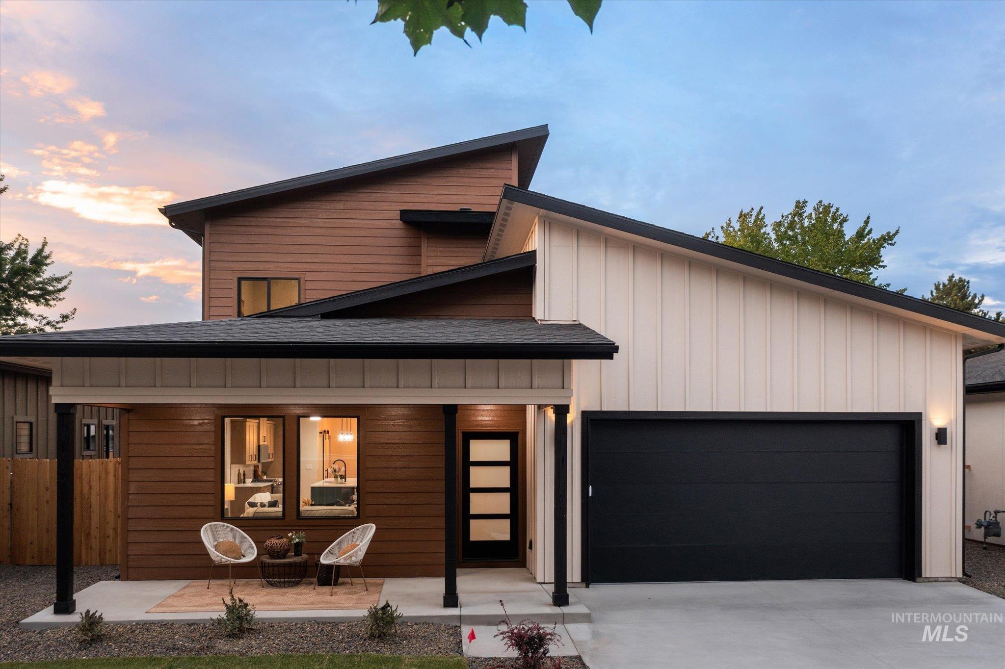 Contemporary house with a porch, an attached garage, roof with shingles, driveway, and board and batten siding