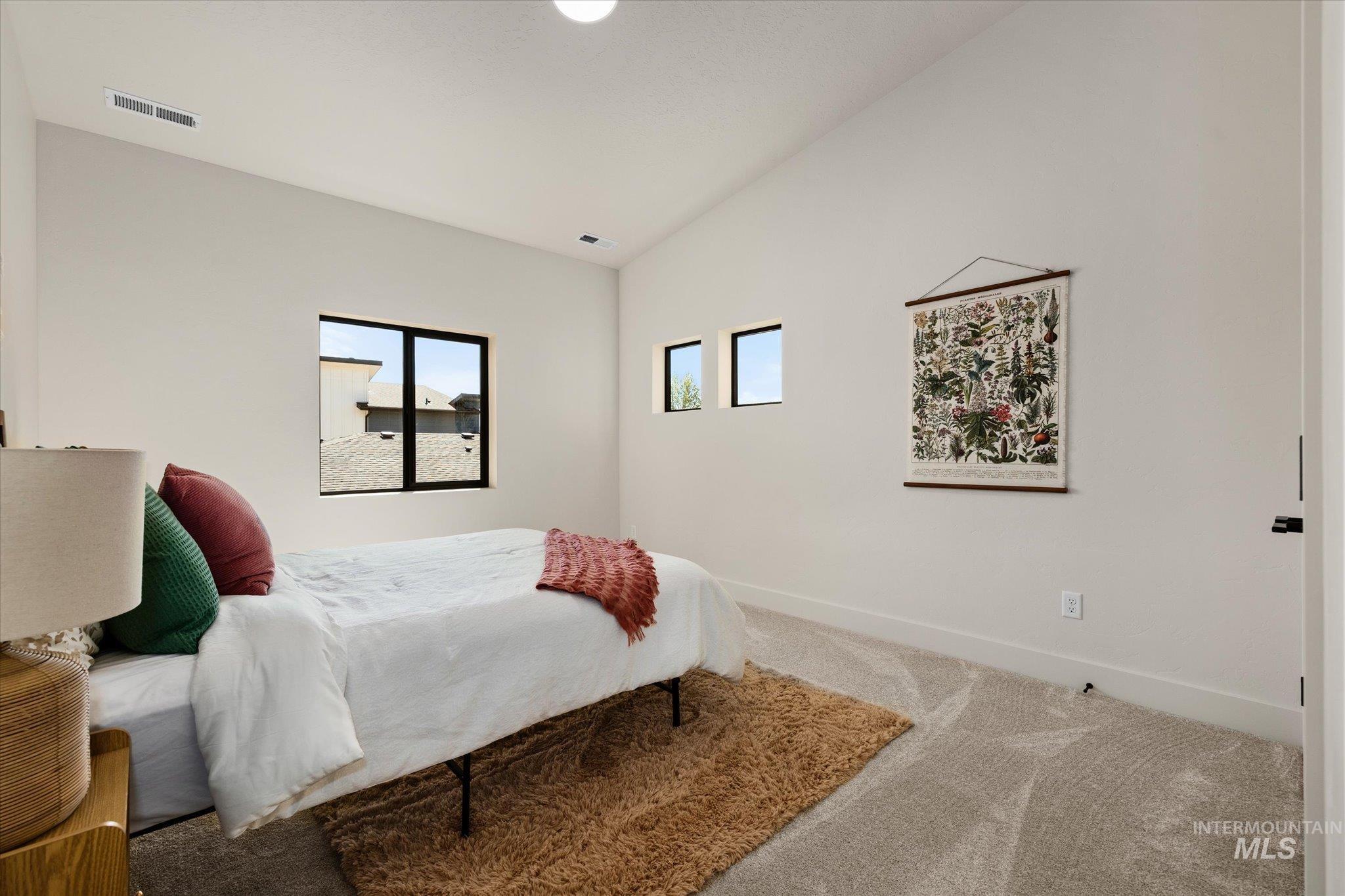 Bedroom with vaulted ceiling and carpet floors