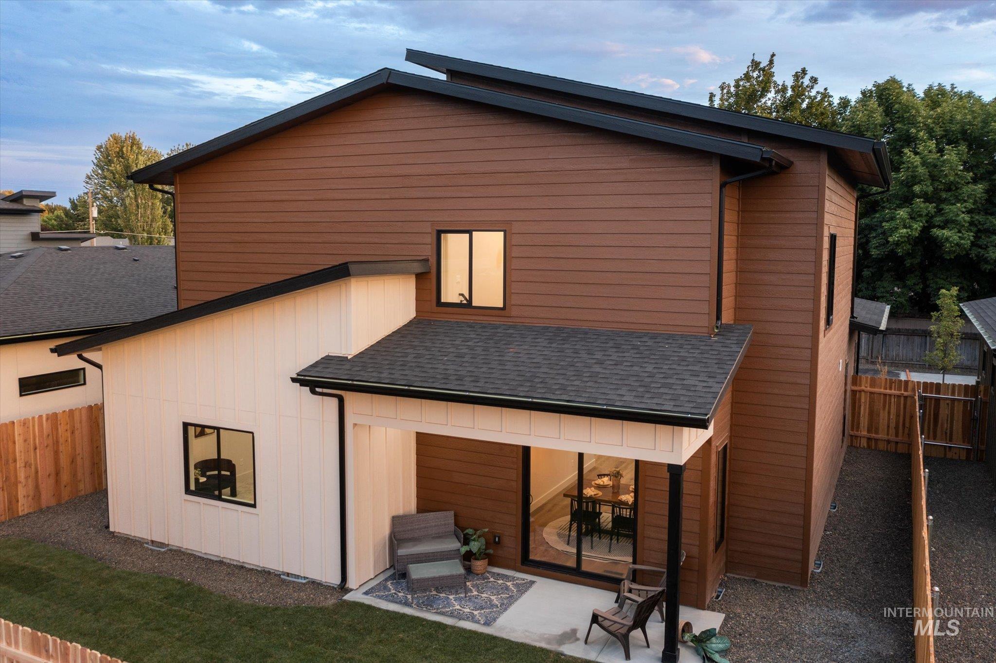 Back of property with roof with shingles and a patio