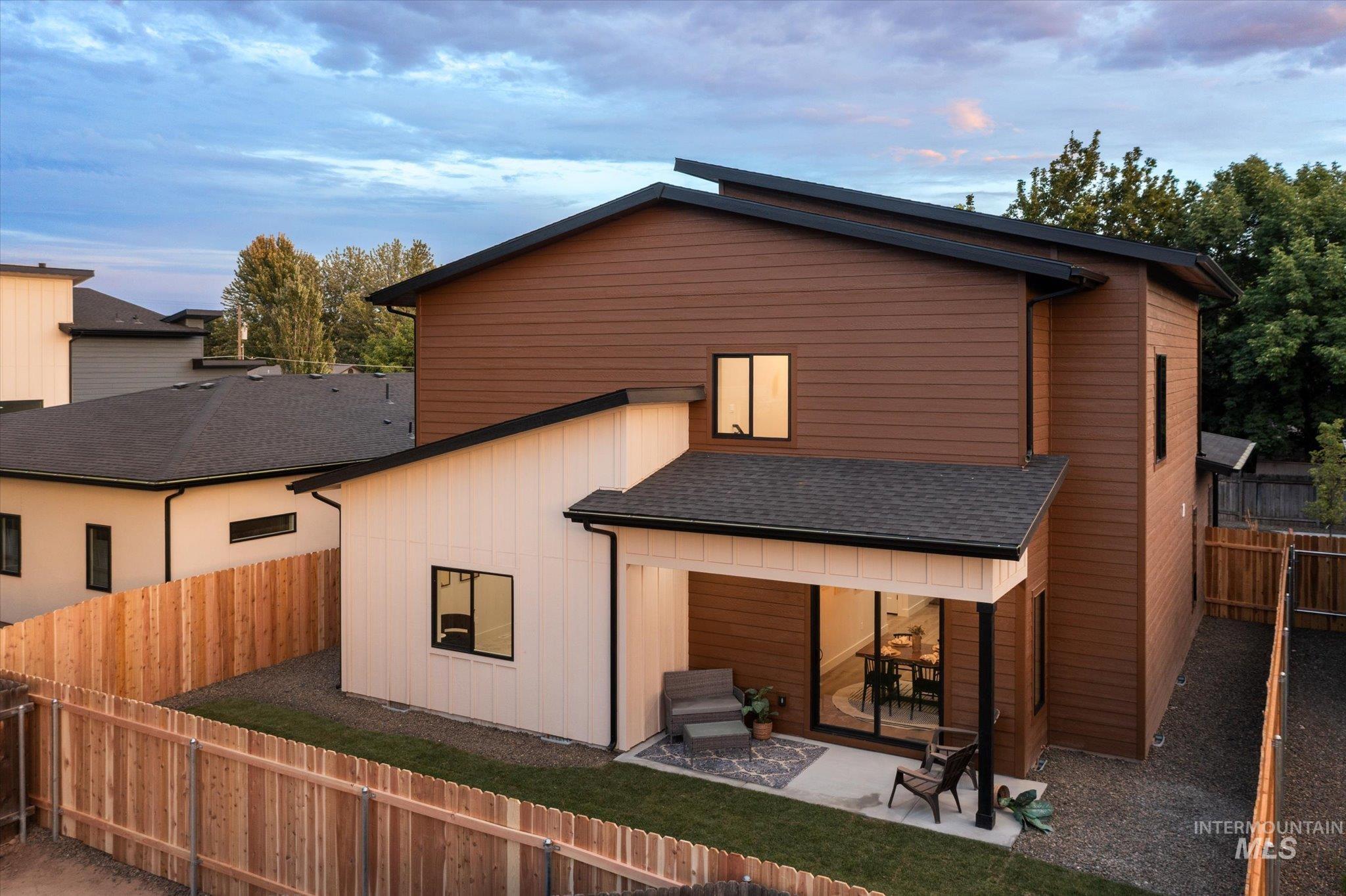 Rear view of property featuring a patio, a fenced backyard, and a shingled roof