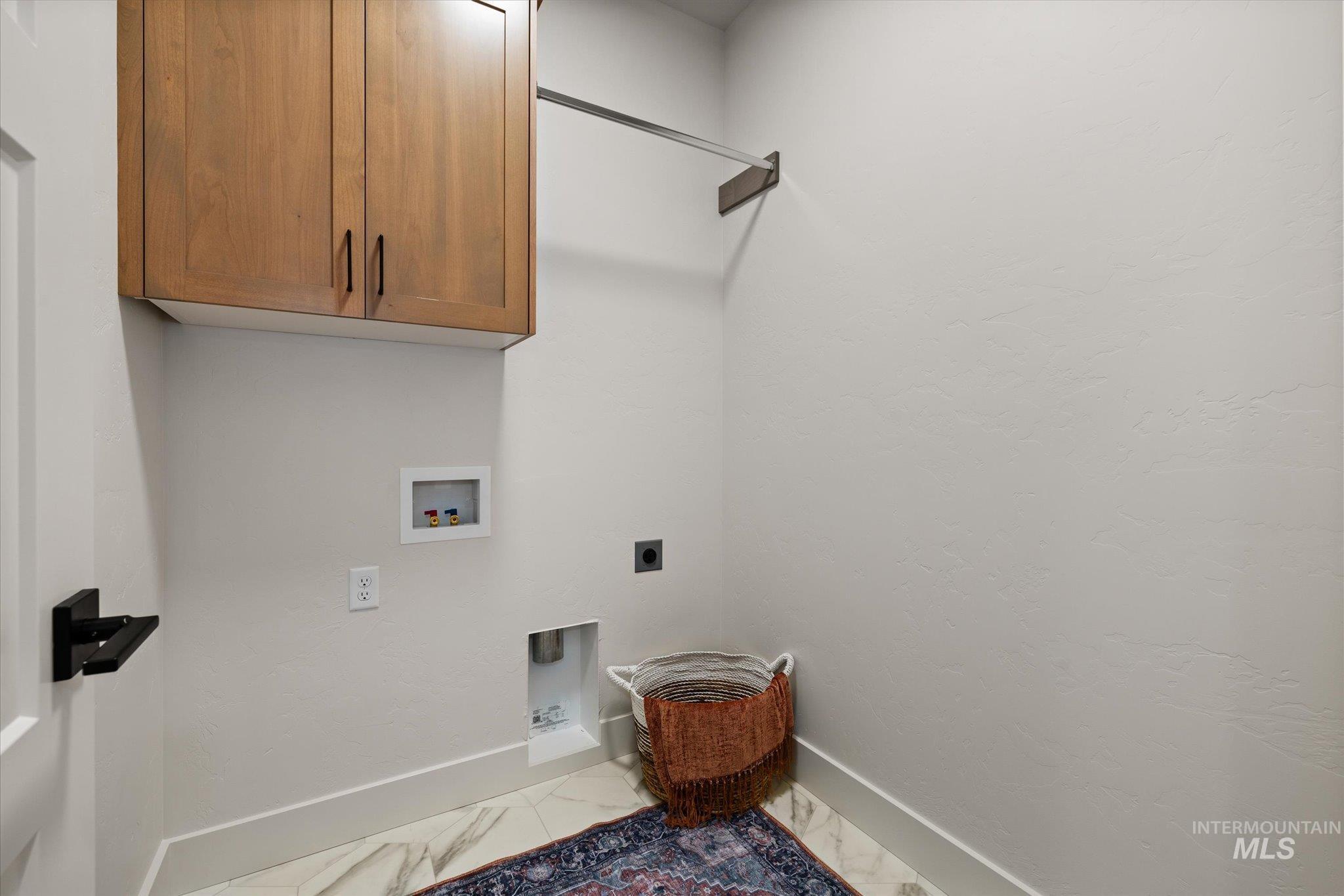 Laundry area with cabinet space, hookup for a washing machine, electric dryer hookup, and marble look tile flooring
