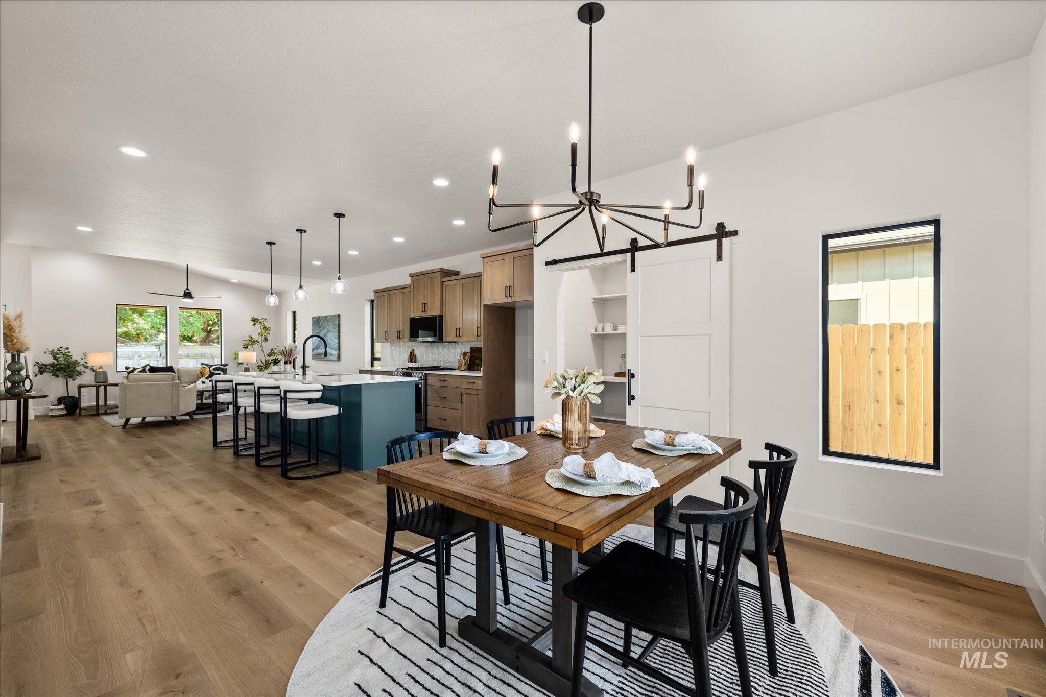 Dining area with a barn door, light wood finished floors, a chandelier, and recessed lighting