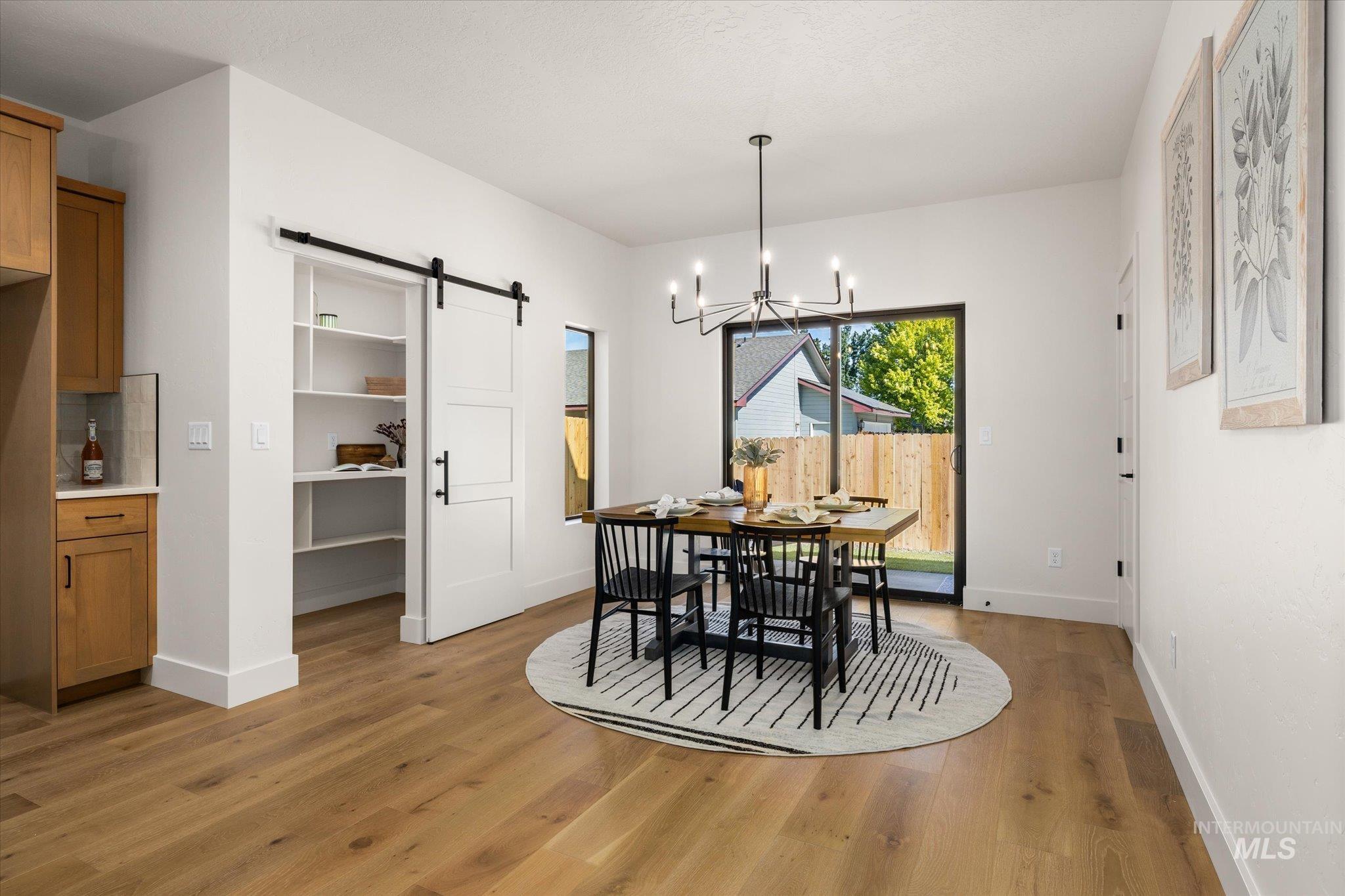 Dining room featuring a barn door, a chandelier, and light wood-type flooring