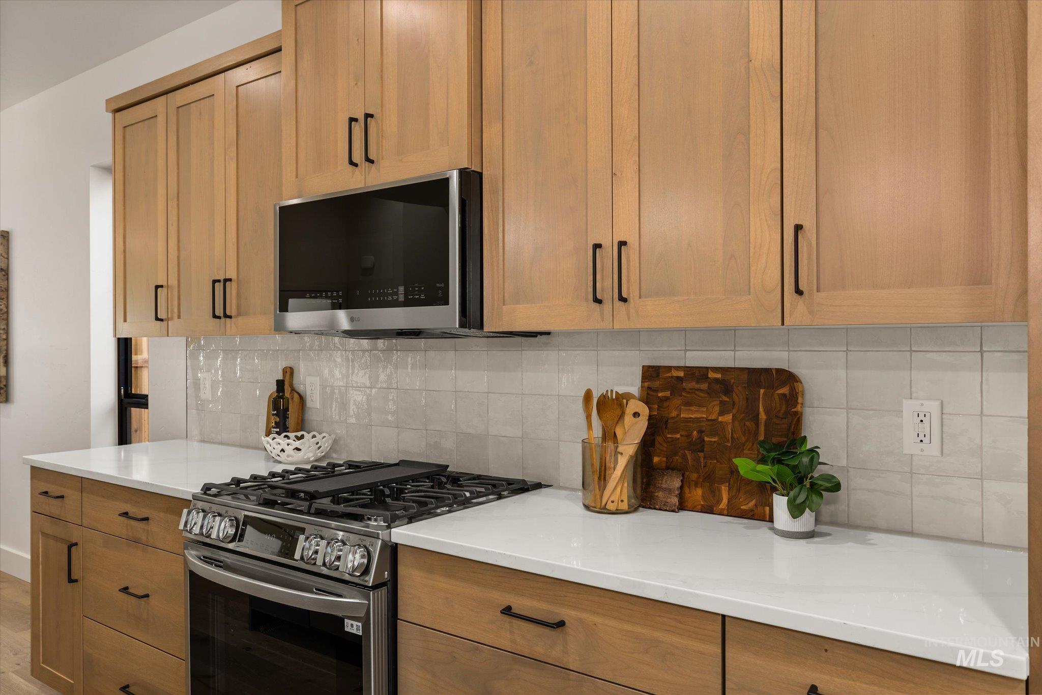 Kitchen with stainless steel appliances, decorative backsplash, and light countertops