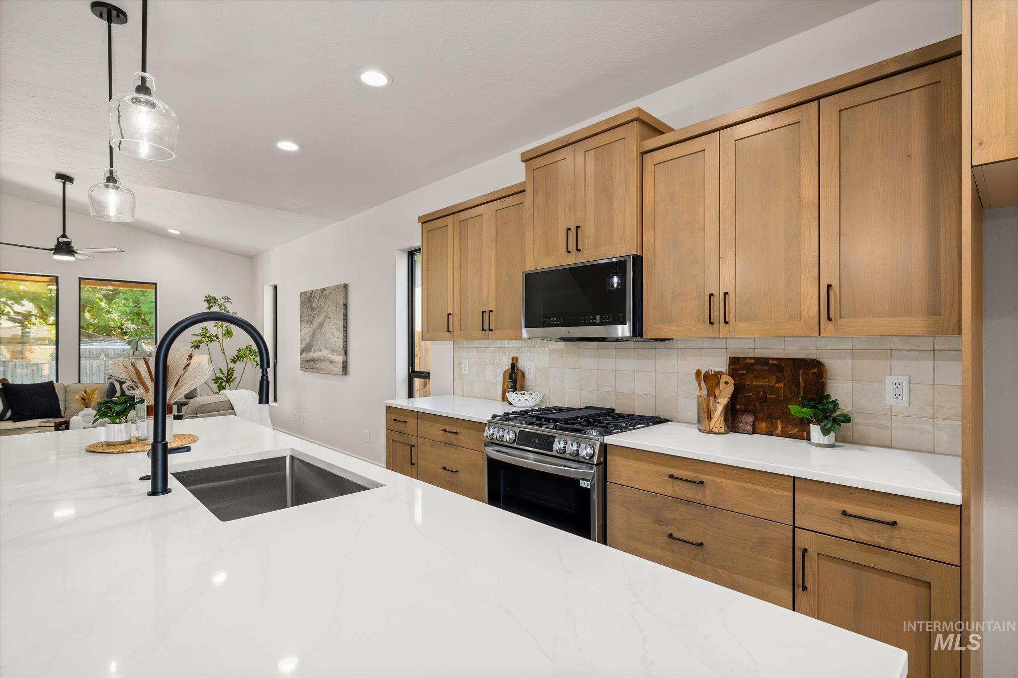 Kitchen with stainless steel appliances, backsplash, brown cabinetry, recessed lighting, and pendant lighting