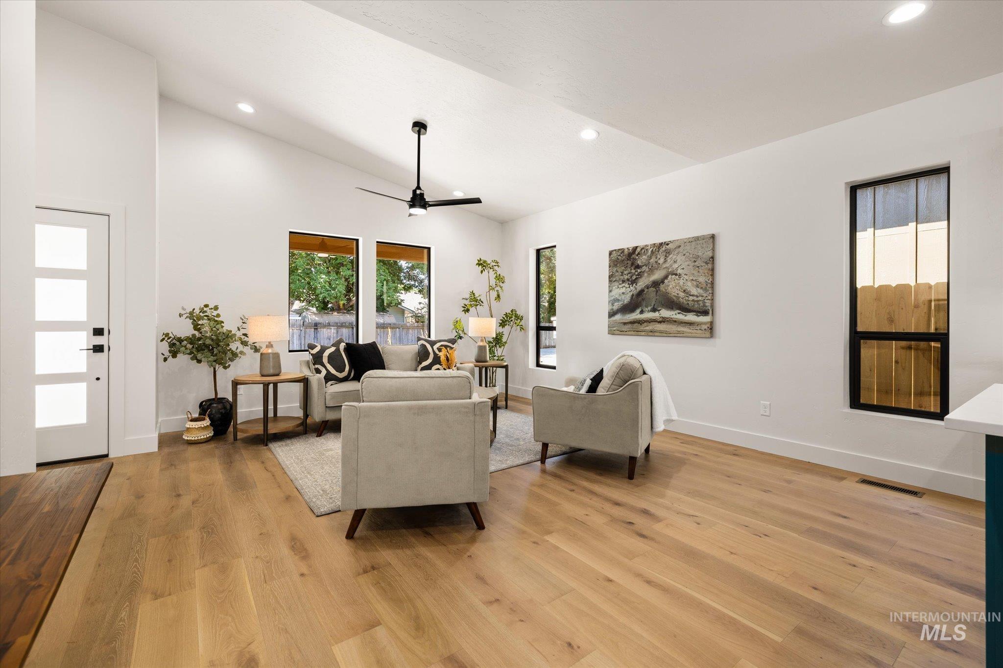 Living room with plenty of natural light, recessed lighting, light wood-style floors, ceiling fan, and high vaulted ceiling