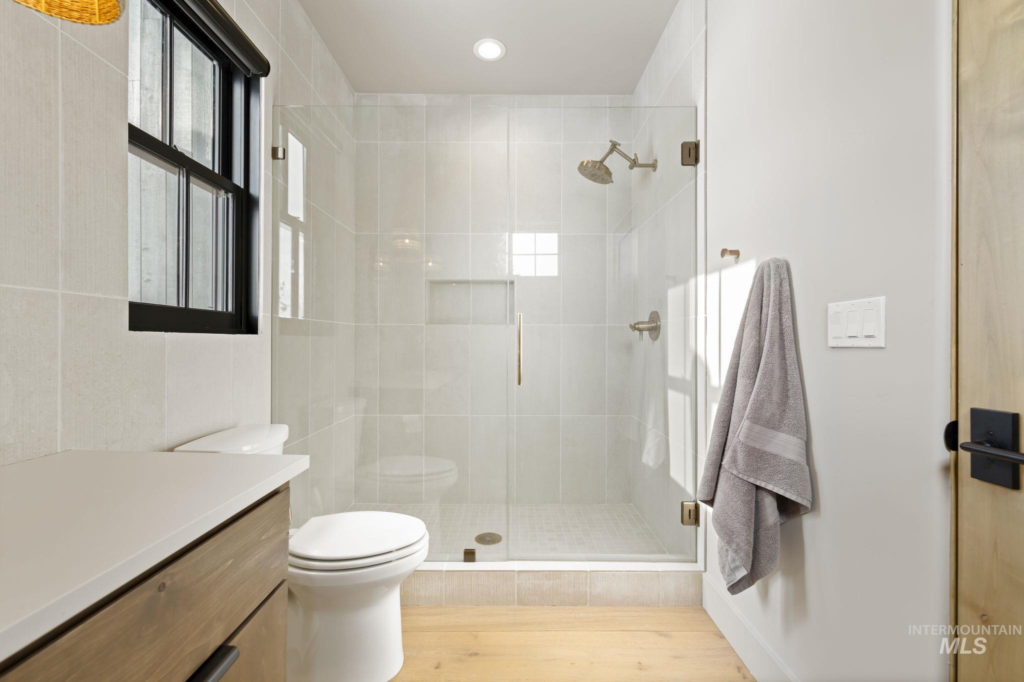 Jr Suite Full bath featuring vanity, a stall shower, and light wood-style flooring
