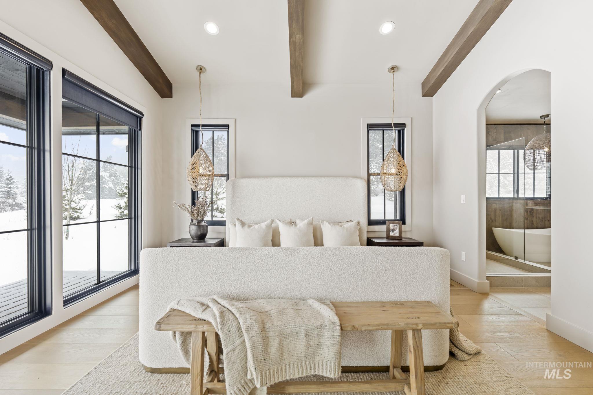 Primary Bedroom featuring access to exterior, light wood-style flooring, recessed lighting, arched walkways, and beam ceiling