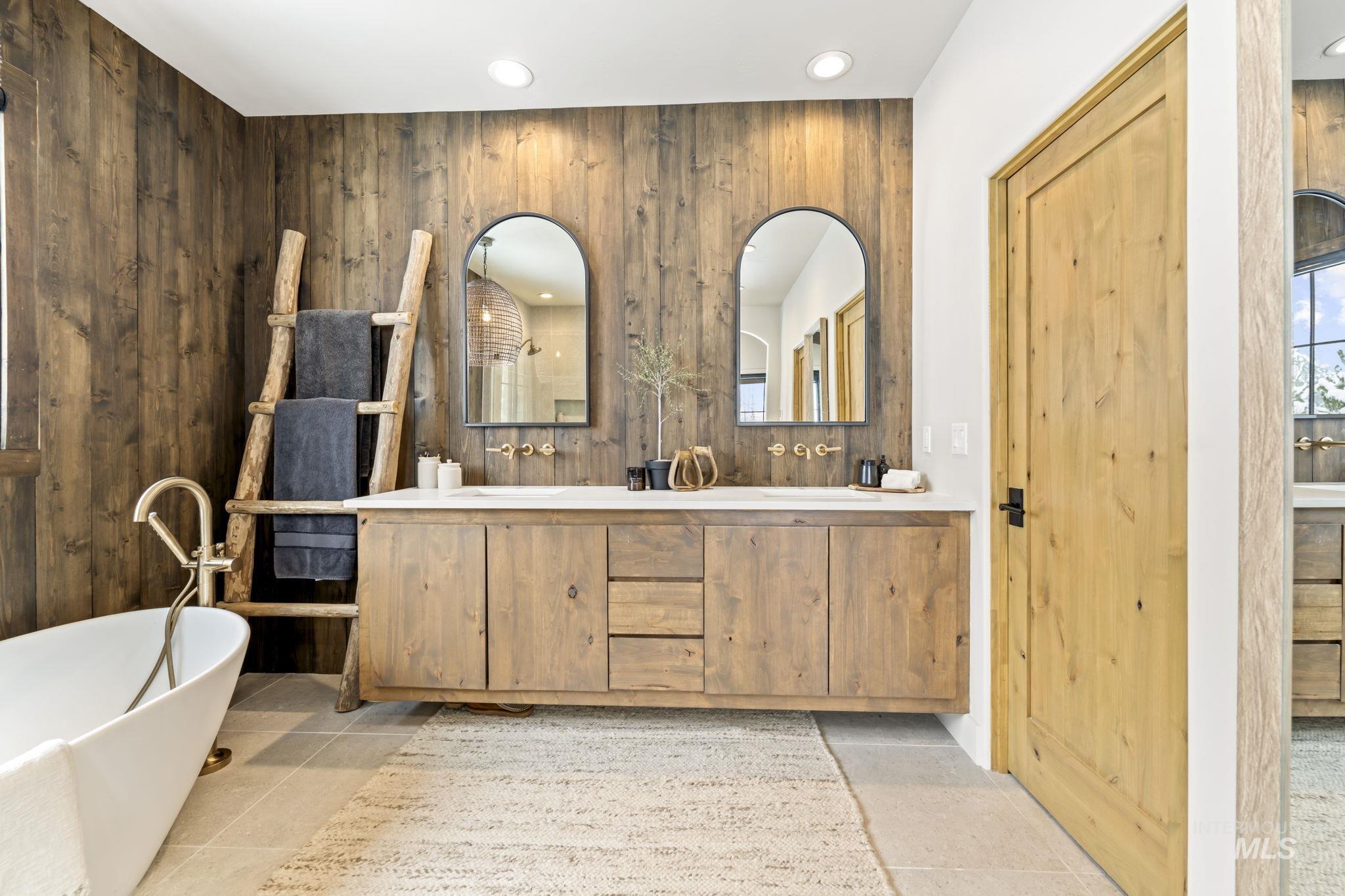 Full bathroom with a soaking tub, double vanity, wood walls, and recessed lighting