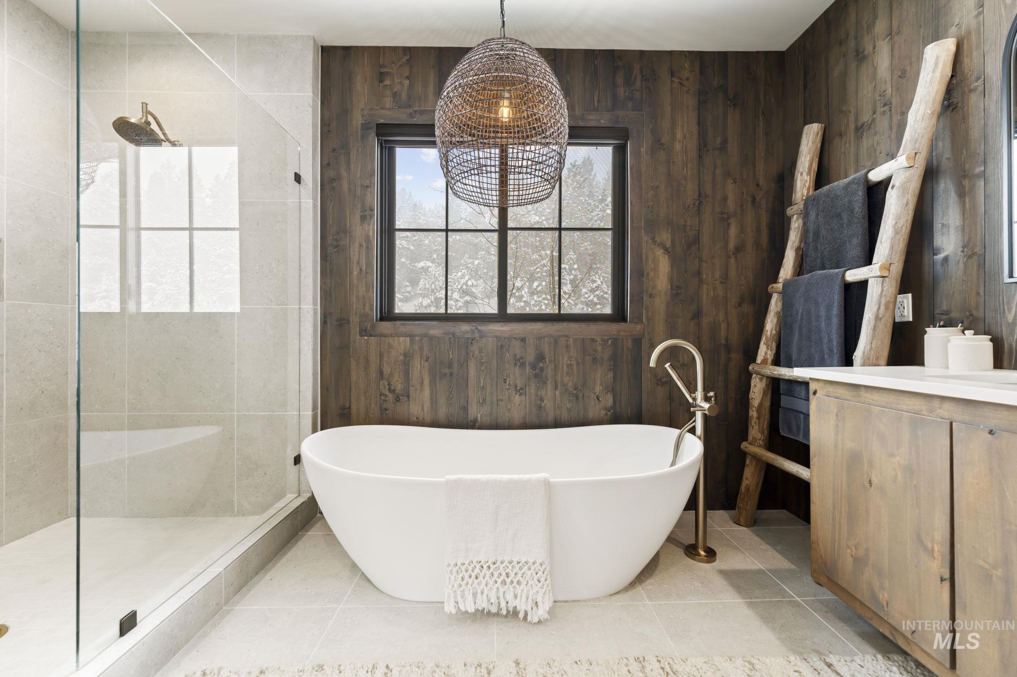Bathroom with a freestanding tub, walk in shower, vanity, wooden walls, and light tile patterned floors