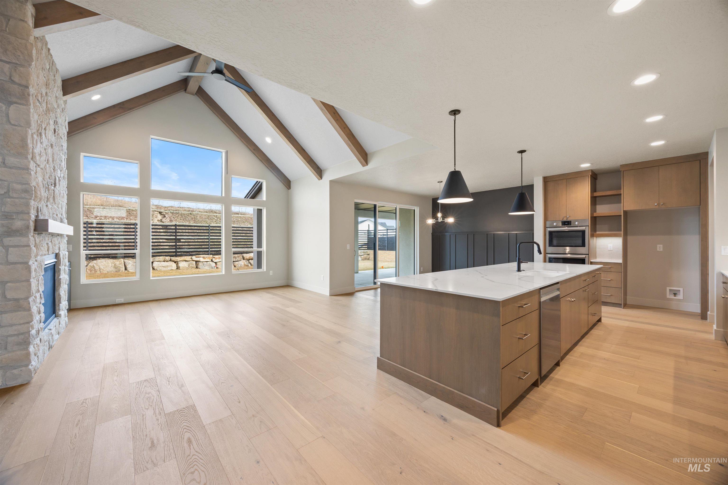 Kitchen with open shelves, a large island, light stone countertops, open floor plan, and light wood-style flooring