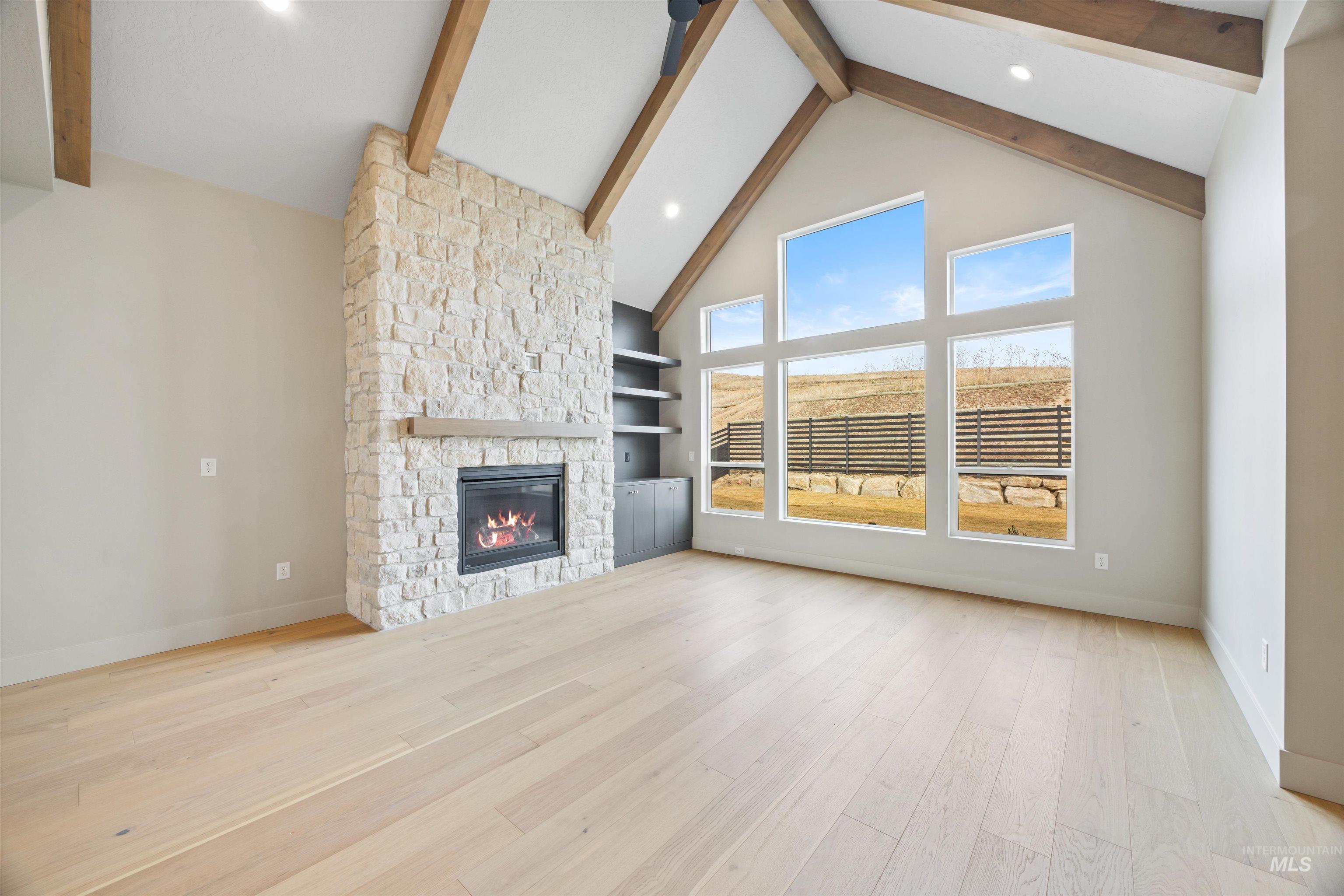 Unfurnished living room featuring a stone fireplace, recessed lighting, light wood finished floors, and built in shelves