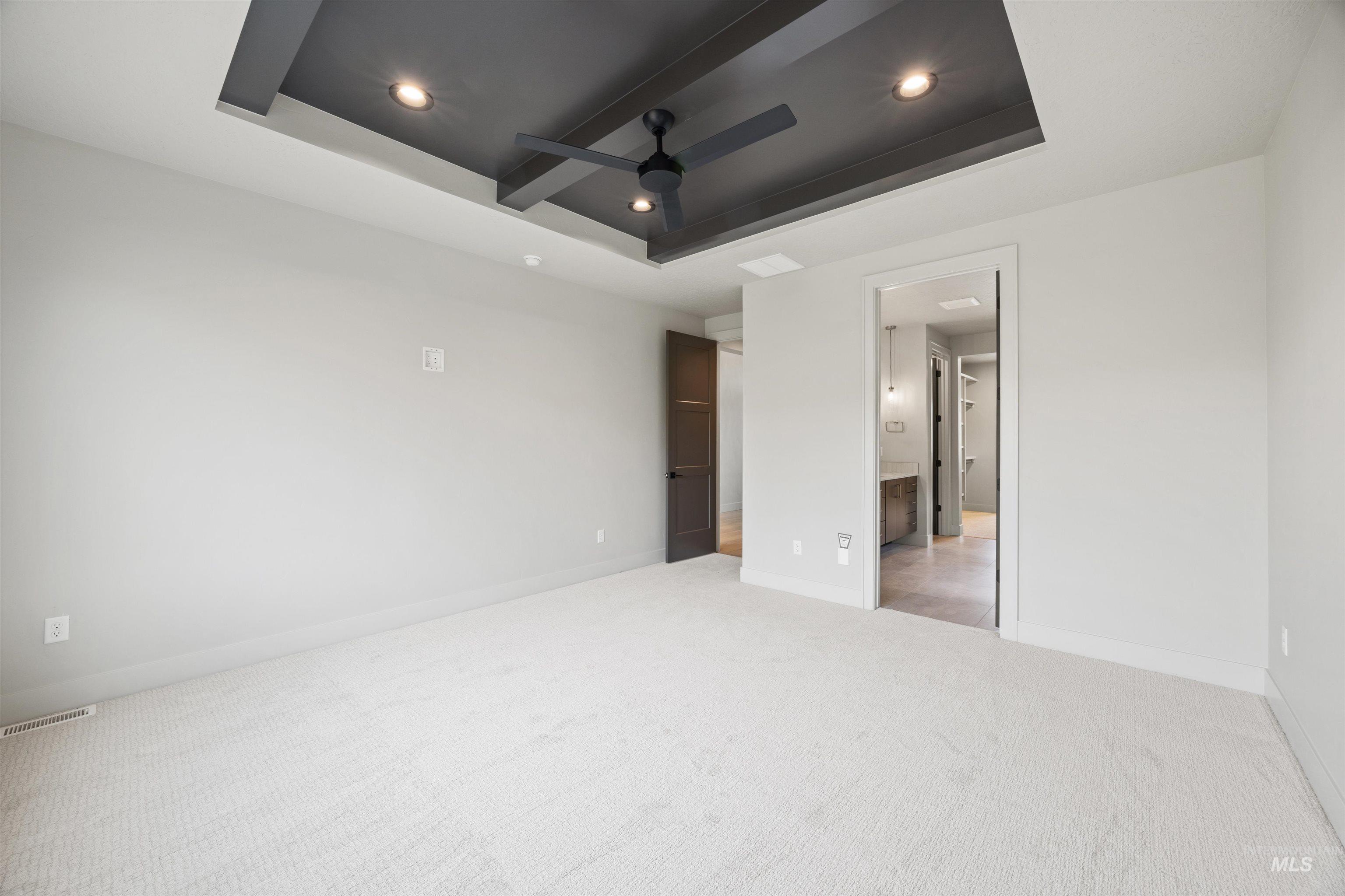 Unfurnished bedroom with carpet floors, a ceiling fan, a raised ceiling, recessed lighting, and ensuite bath
