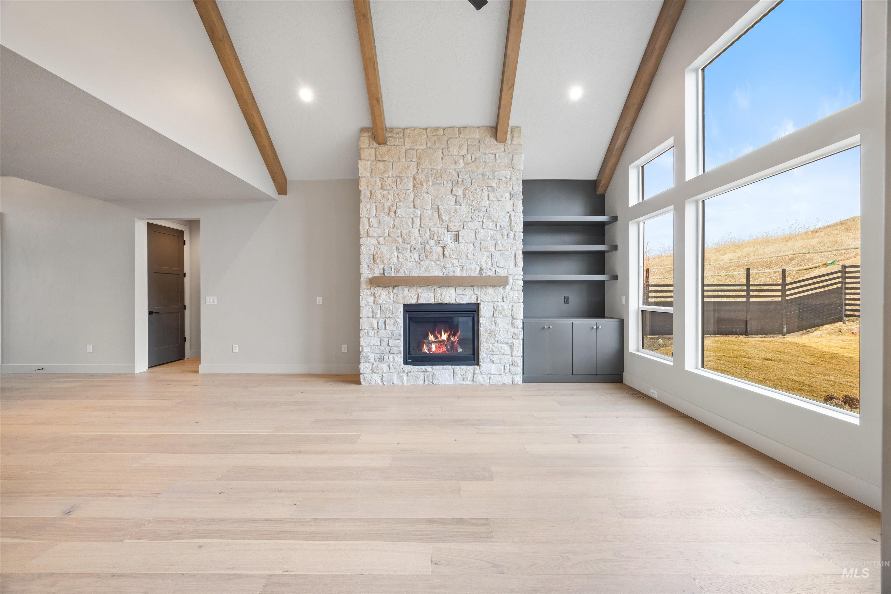 Unfurnished living room featuring a fireplace, light wood-type flooring, vaulted ceiling, recessed lighting, and built in shelves