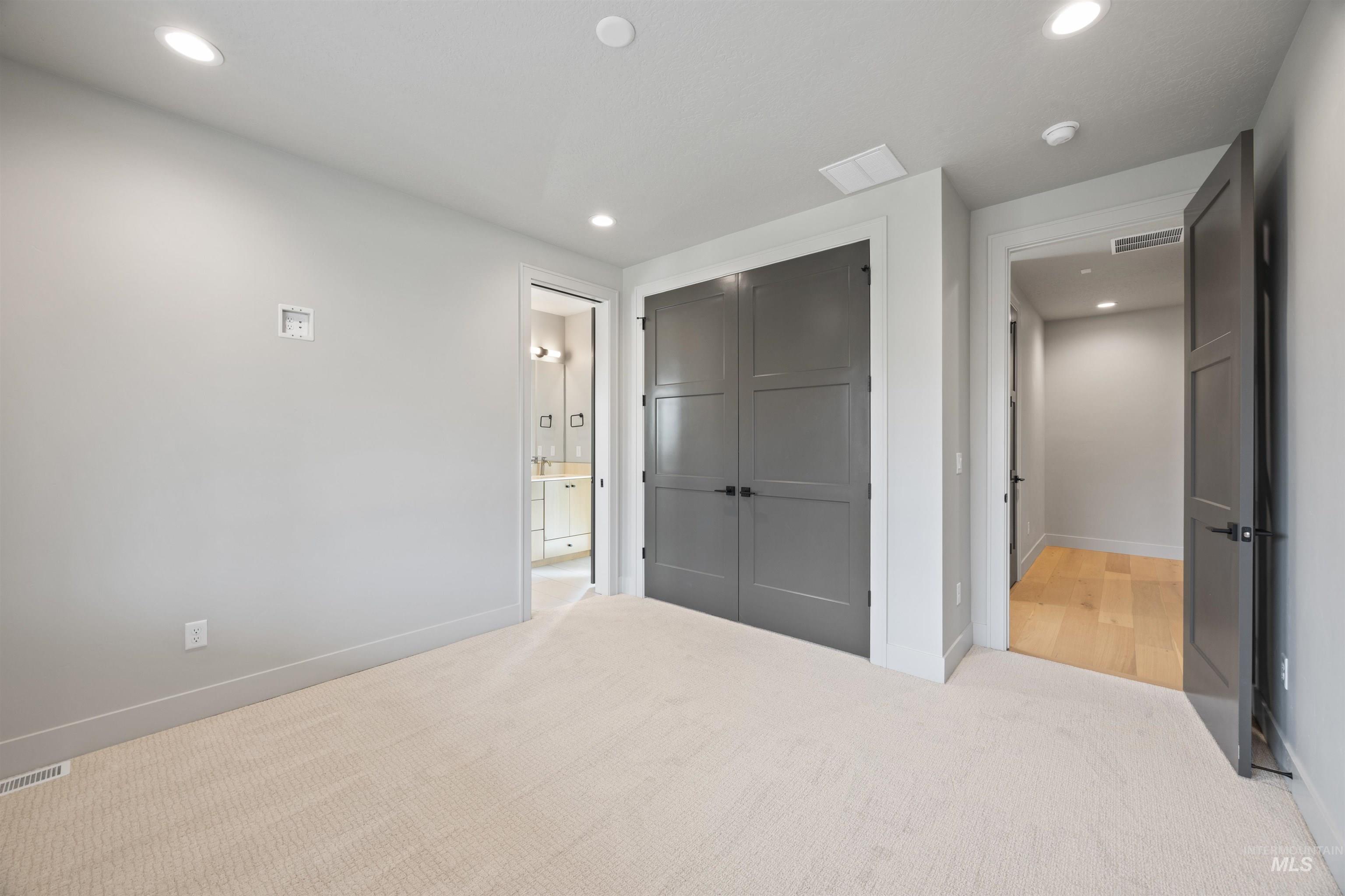 Unfurnished bedroom with a closet, light colored carpet, and recessed lighting