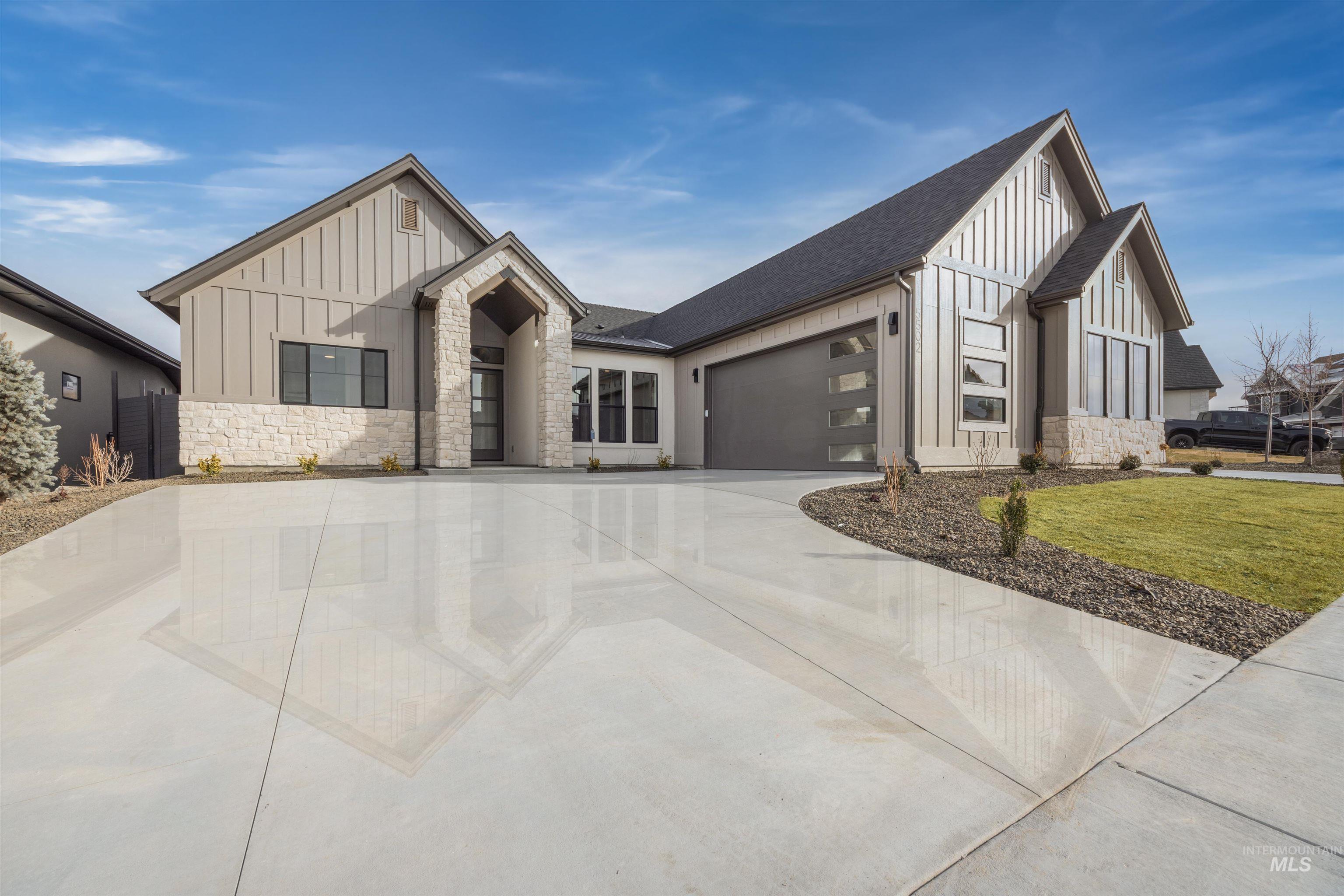 Modern inspired farmhouse featuring board and batten siding, stone siding, a garage, and roof with shingles