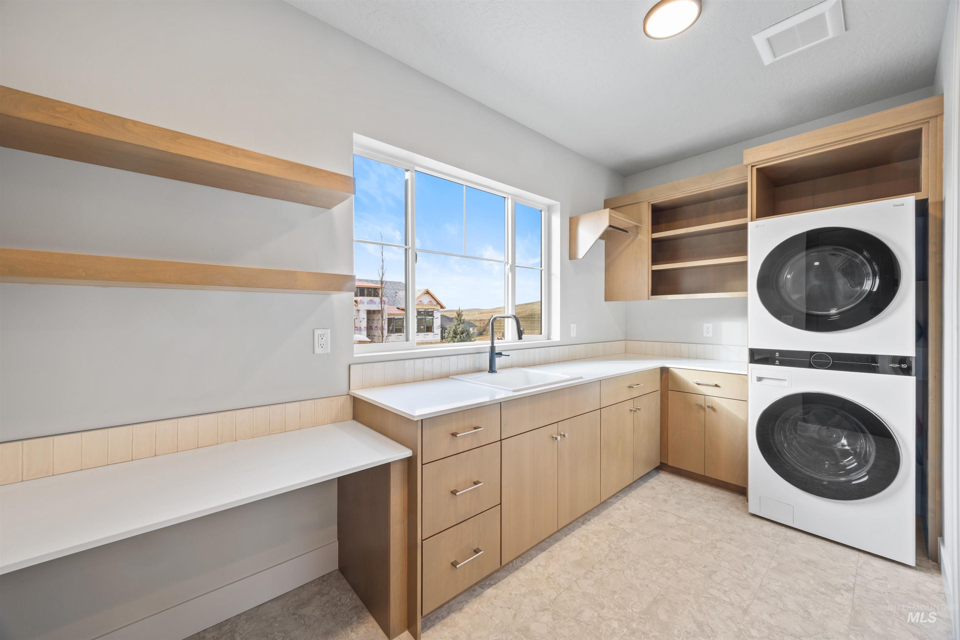 Laundry area featuring stacked washing machine and dryer and cabinet space