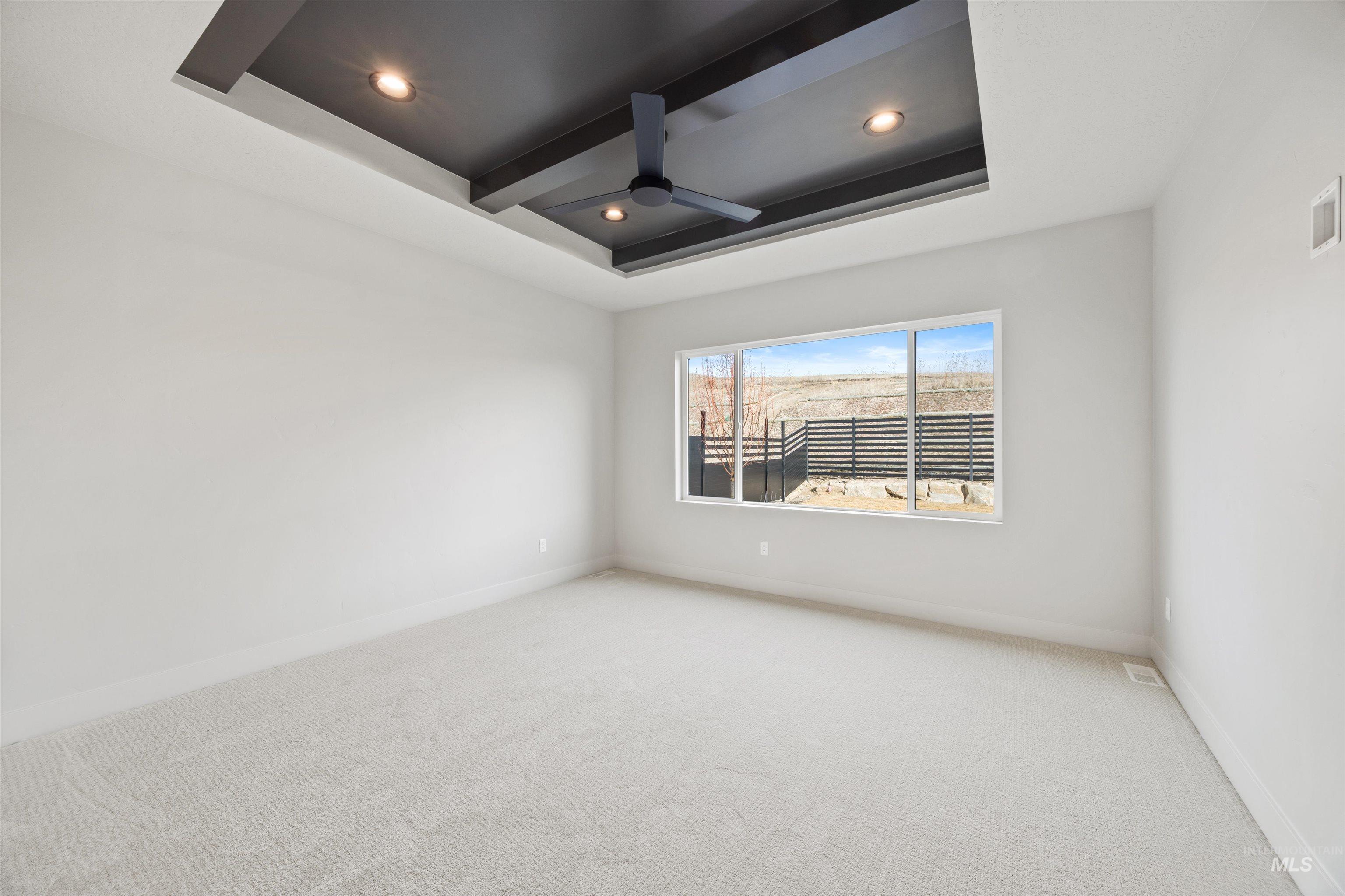 Spare room featuring carpet floors, a raised ceiling, a ceiling fan, recessed lighting, and beamed ceiling