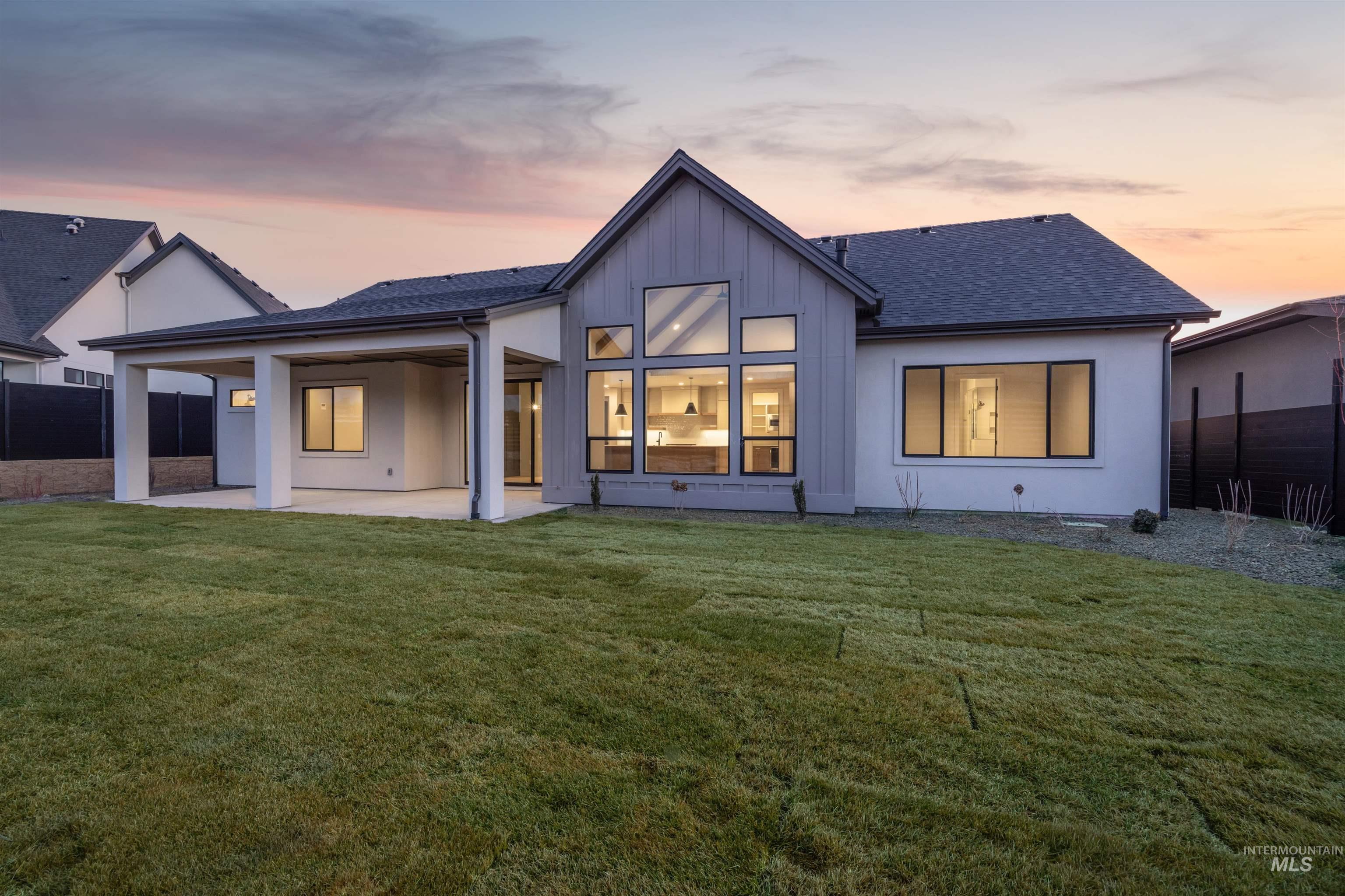 Back of property at dusk featuring a patio area, roof with shingles, and board and batten siding