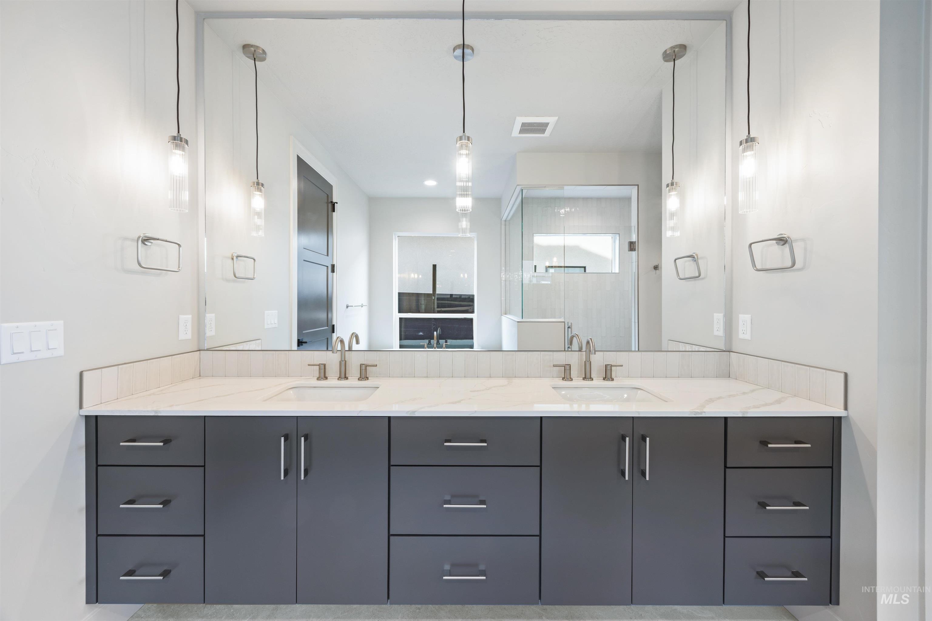 Bathroom with double vanity, a shower stall, and recessed lighting