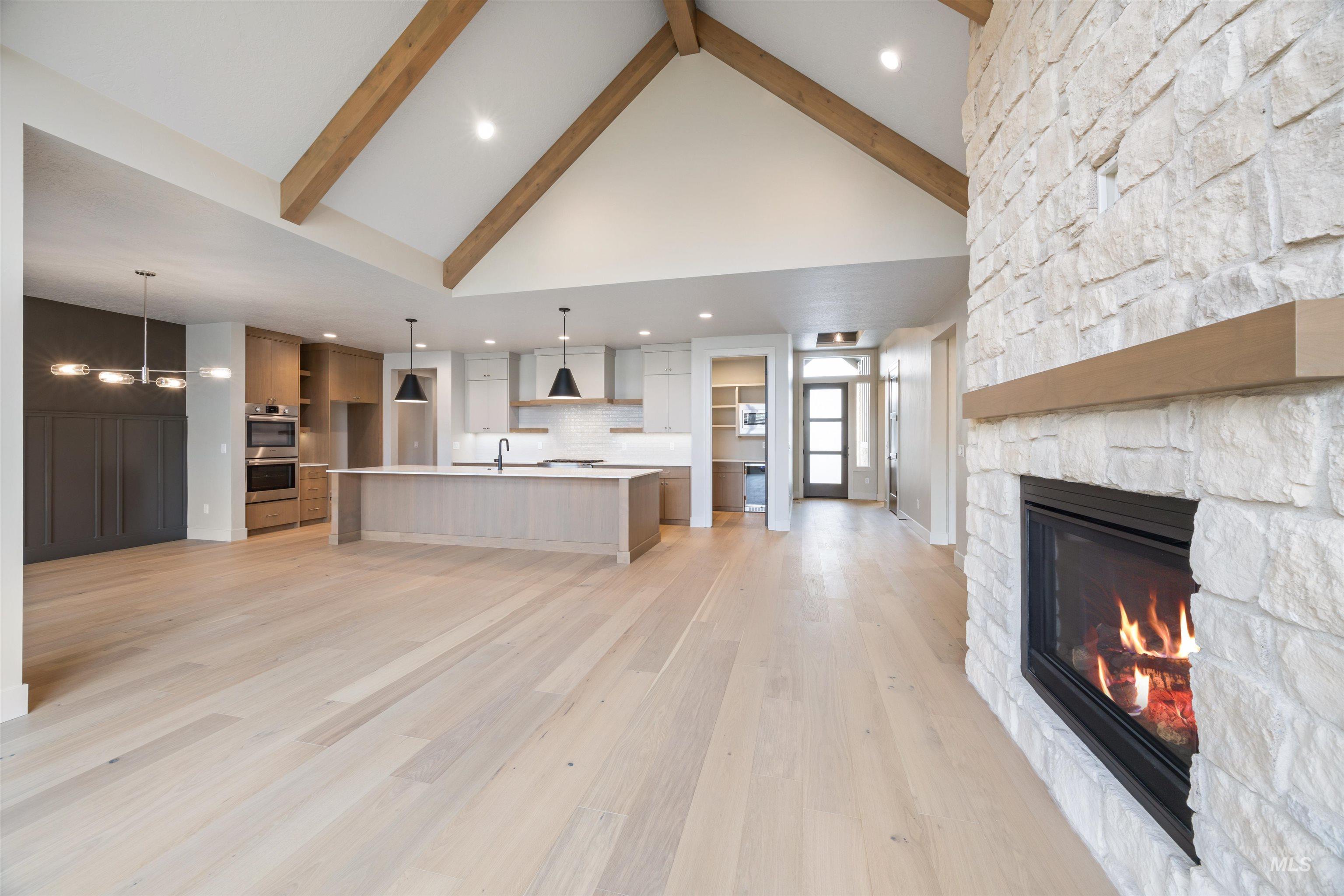 Unfurnished living room featuring light wood finished floors, suspended lighting, and a fireplace