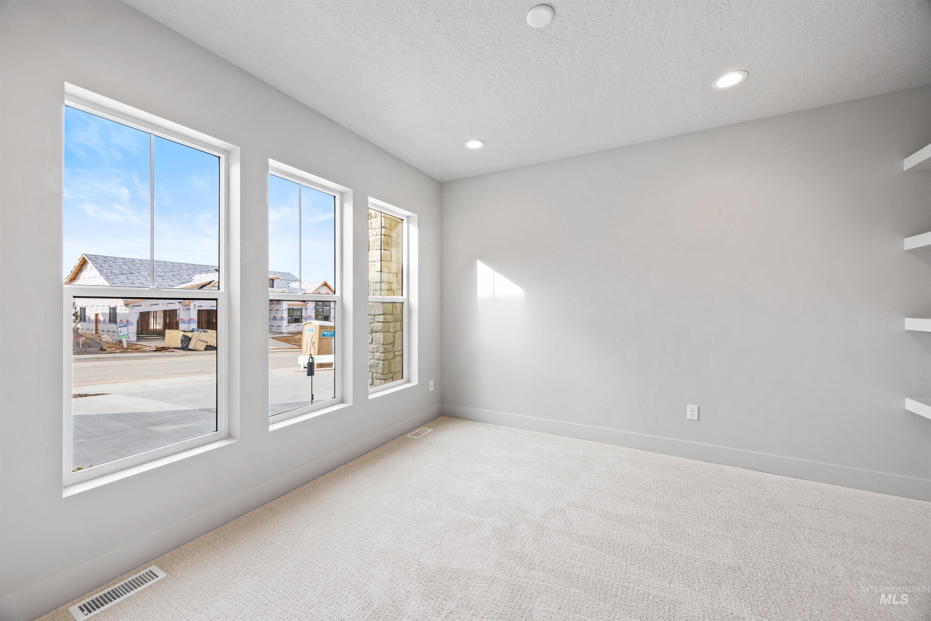 Spare room with light colored carpet, a textured ceiling, and recessed lighting