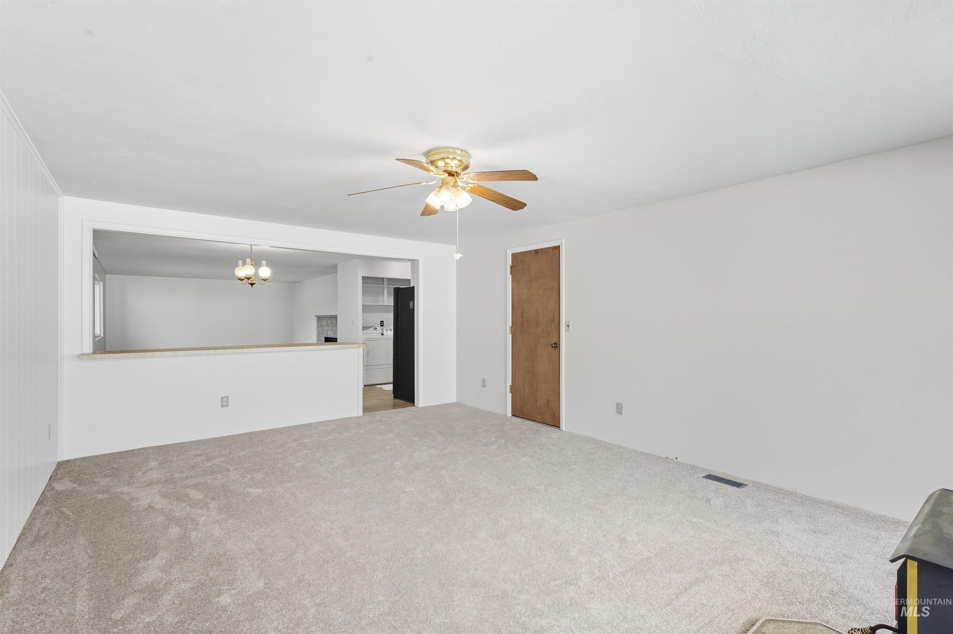 Unfurnished living room featuring a chandelier, carpet flooring, and a ceiling fan