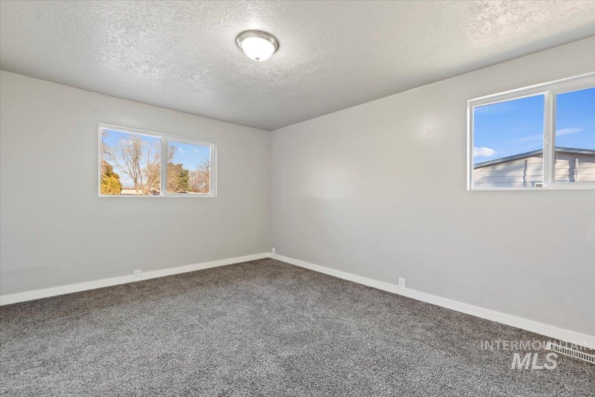 Empty room featuring a textured ceiling and carpet flooring