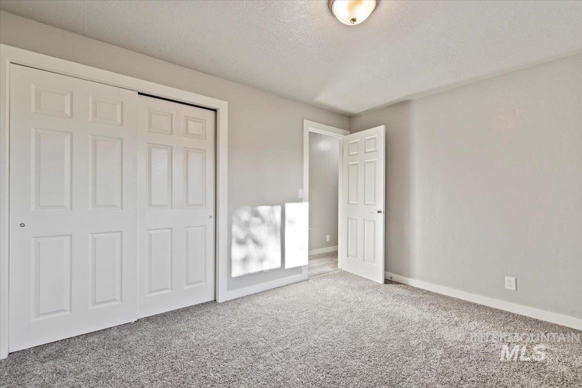Unfurnished bedroom featuring a textured ceiling, a closet, and carpet