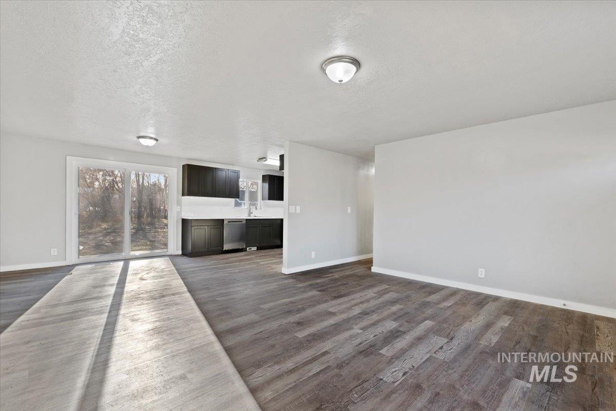 Unfurnished living room featuring a textured ceiling and dark wood-type flooring