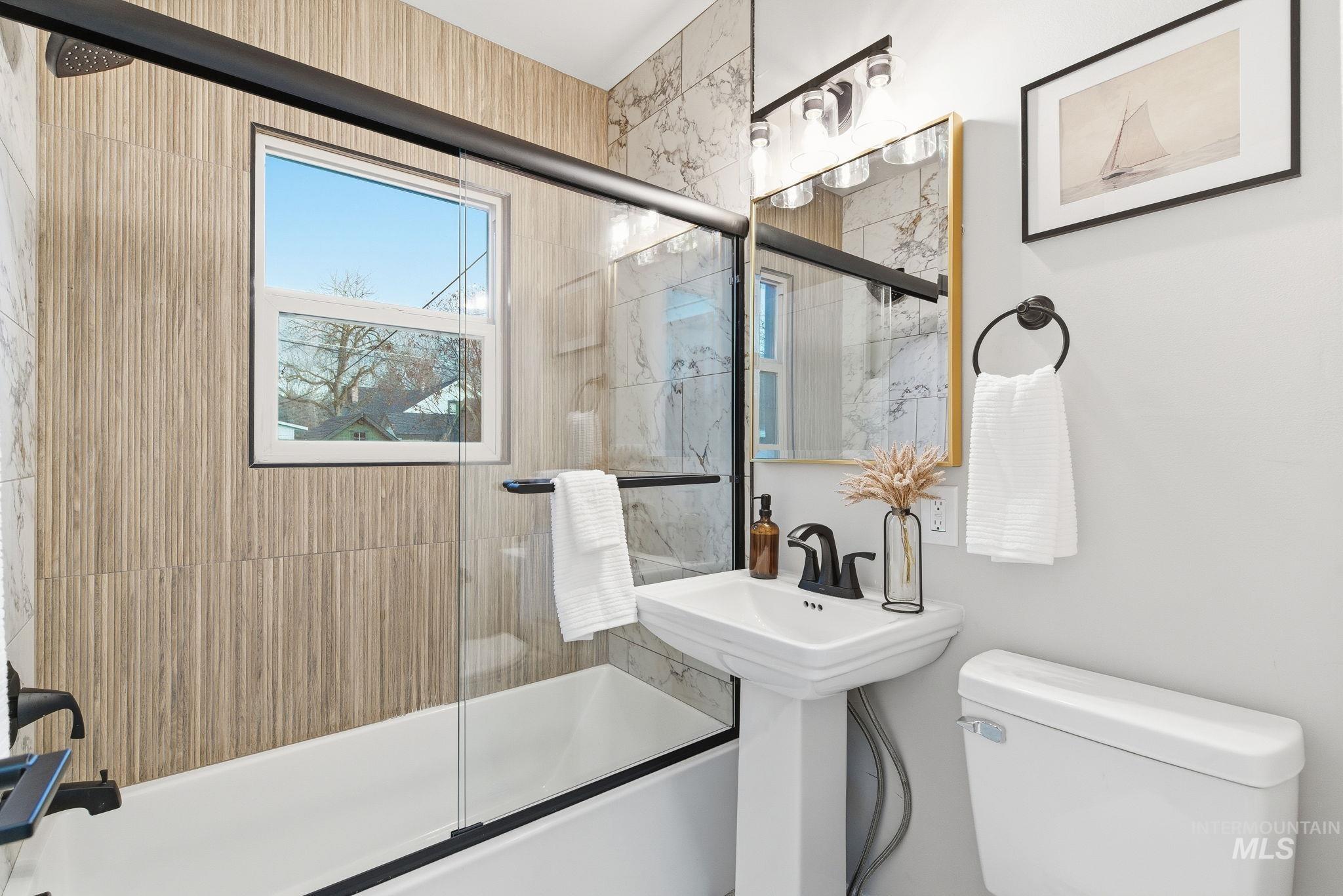 Bathroom featuring bath / shower combo with glass door and toilet