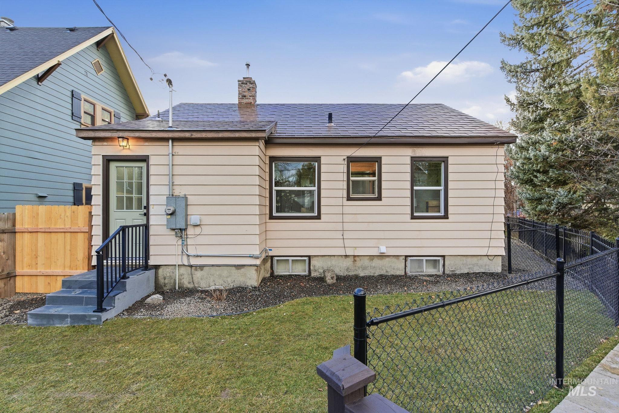 Rear view of property with a fenced backyard, a chimney, and a shingled roof