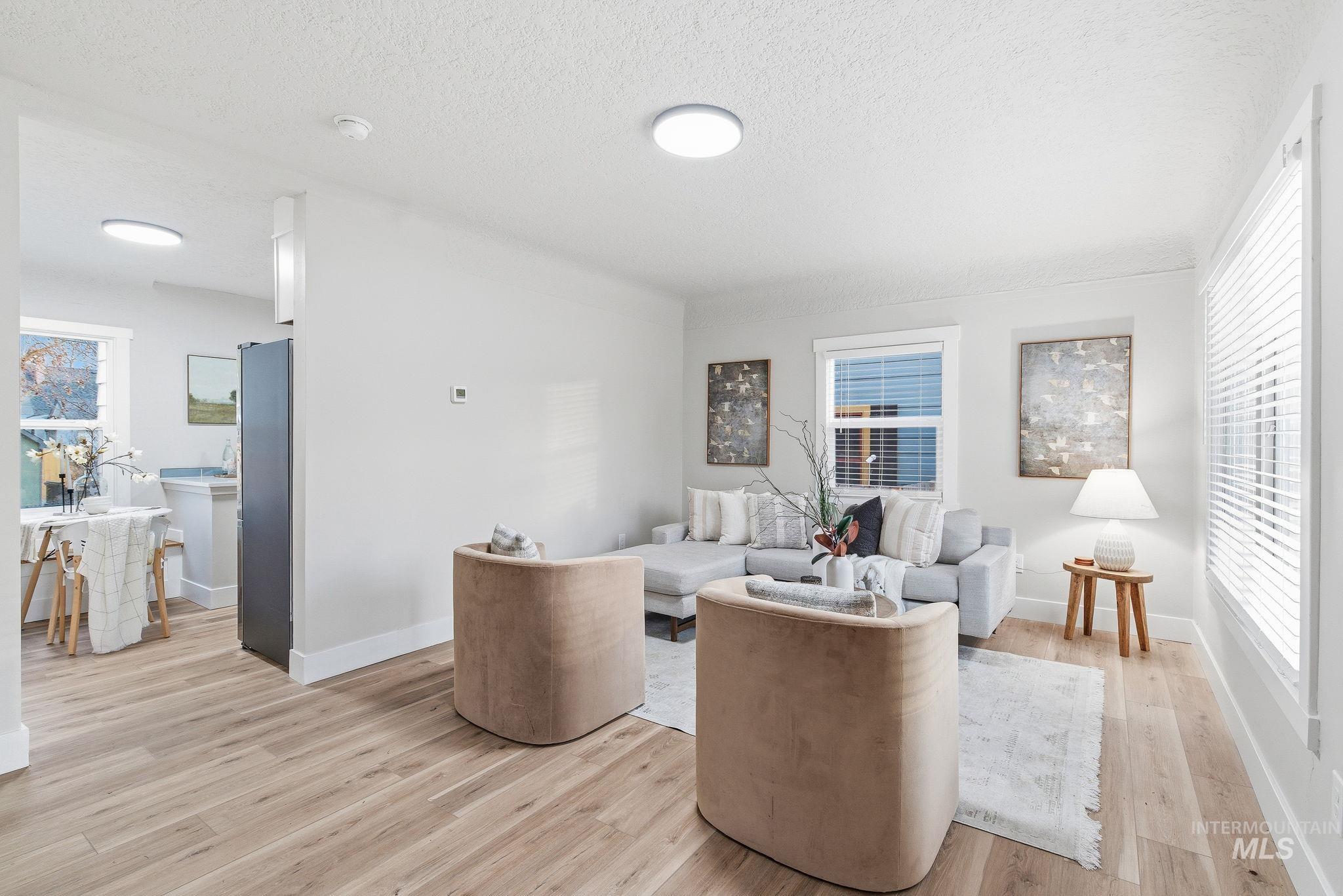 Living room featuring healthy amount of natural light, a textured ceiling, and light wood-style floors