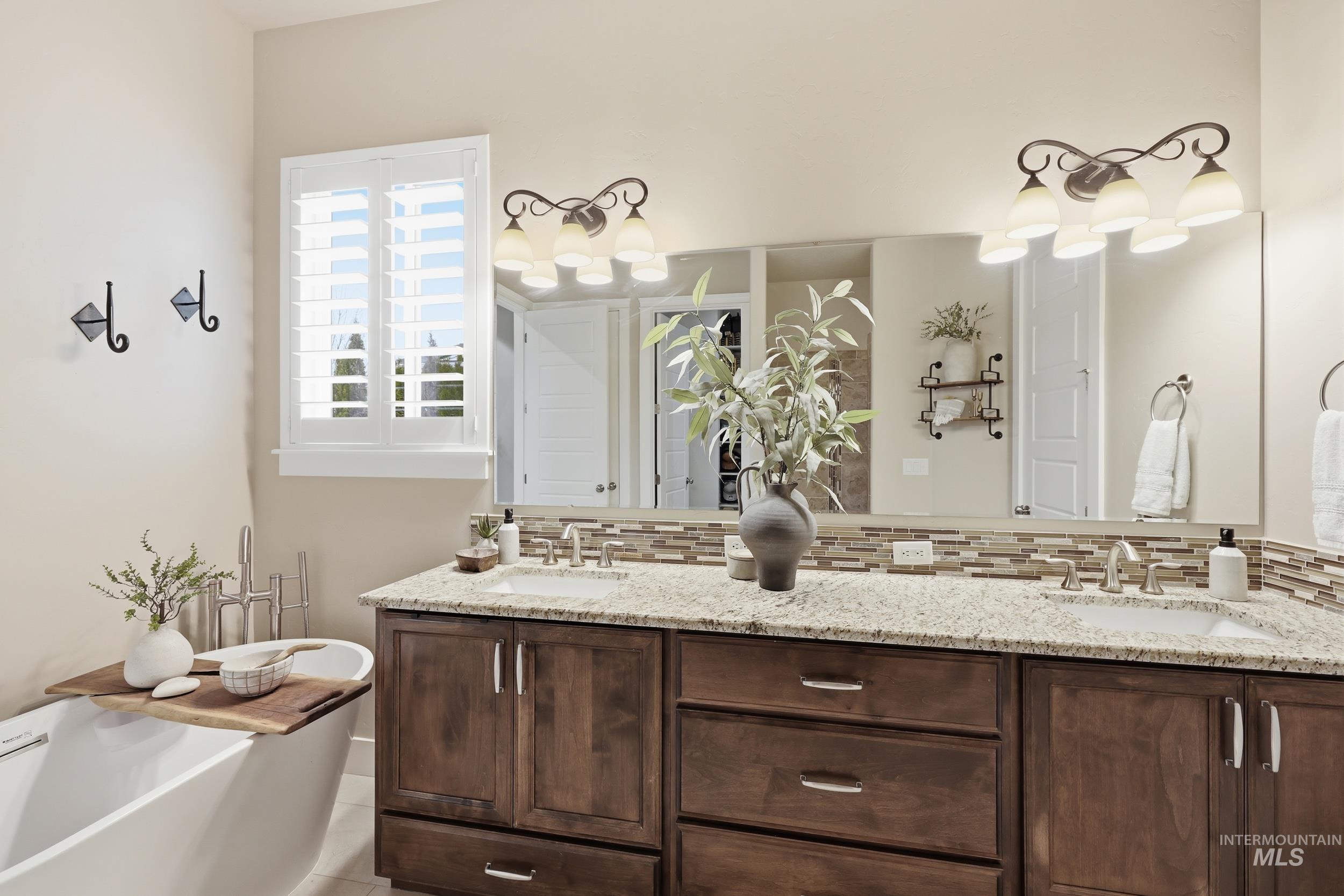 Bathroom featuring backsplash, a freestanding tub, and double vanity