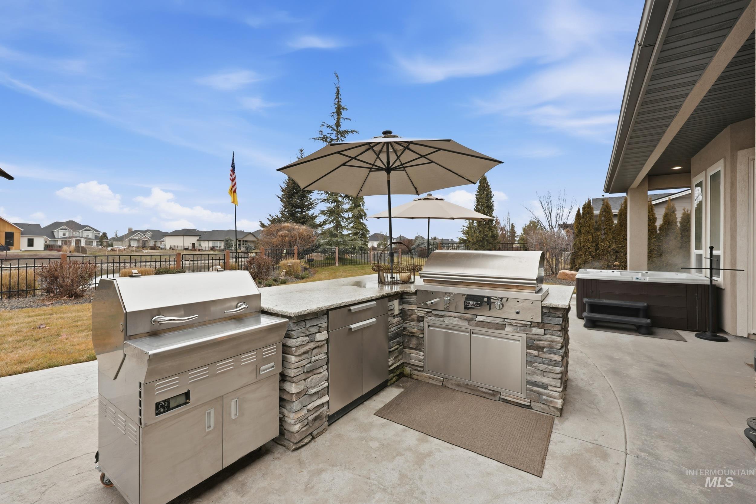 View of patio featuring a residential view, exterior kitchen, and a hot tub