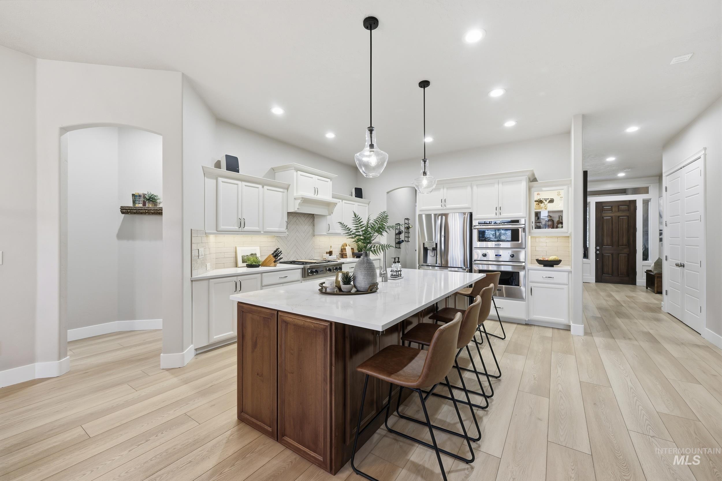 Kitchen featuring white cabinetry, light wood-style flooring, a breakfast bar, a kitchen island, and recessed lighting