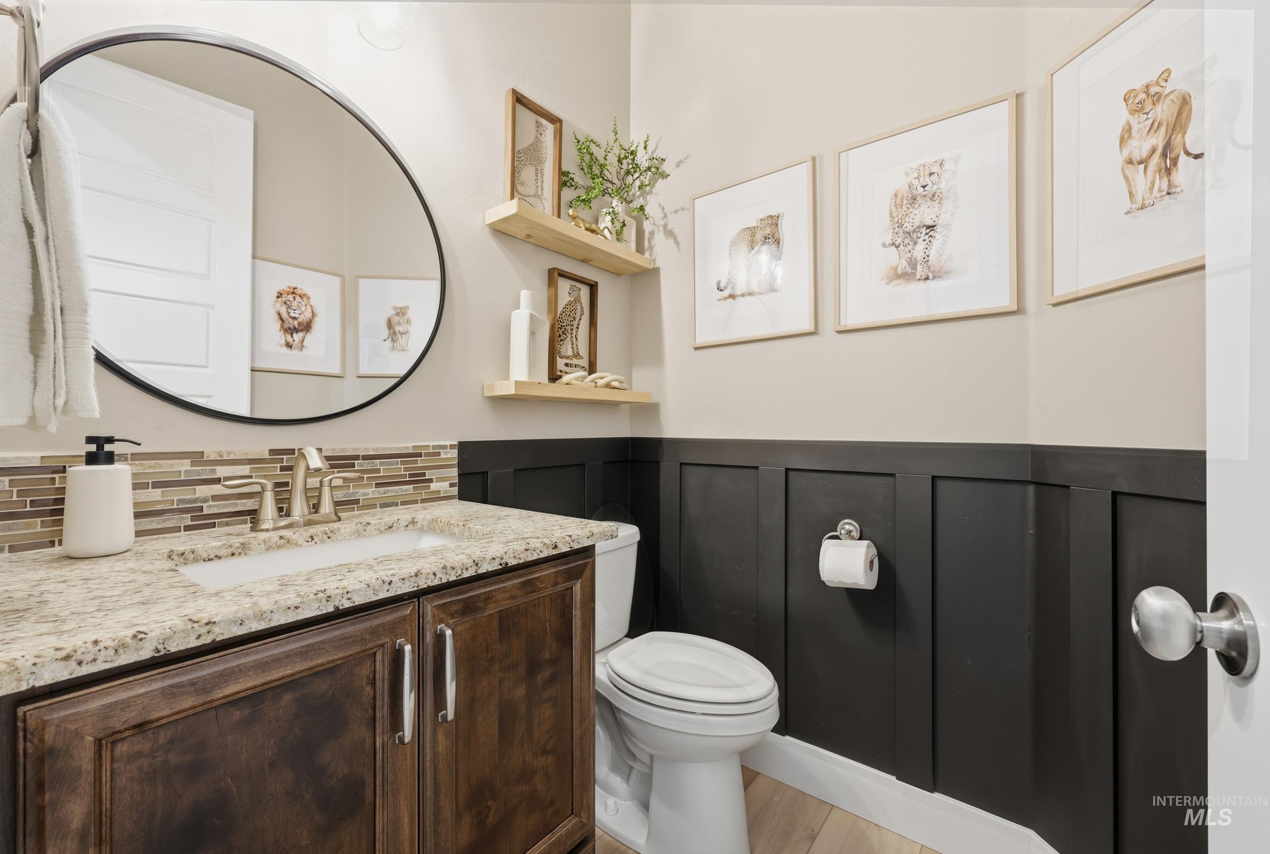 Half bath featuring vanity, light wood finished floors, backsplash, and wainscoting
