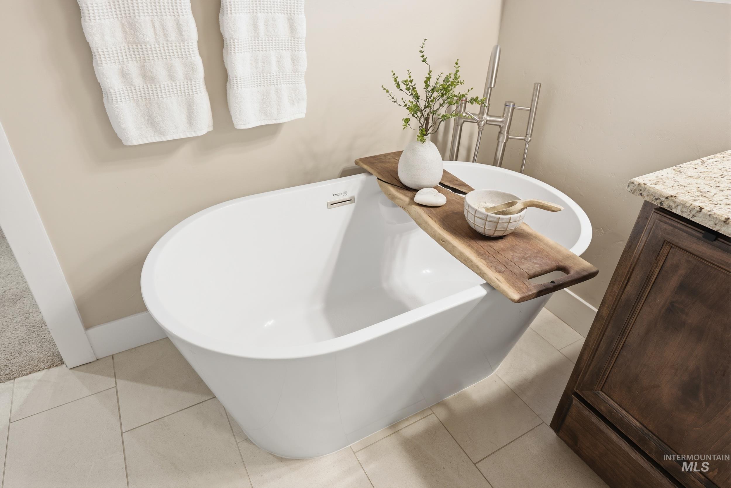 Full bathroom featuring vanity, a freestanding bath, and light tile patterned floors