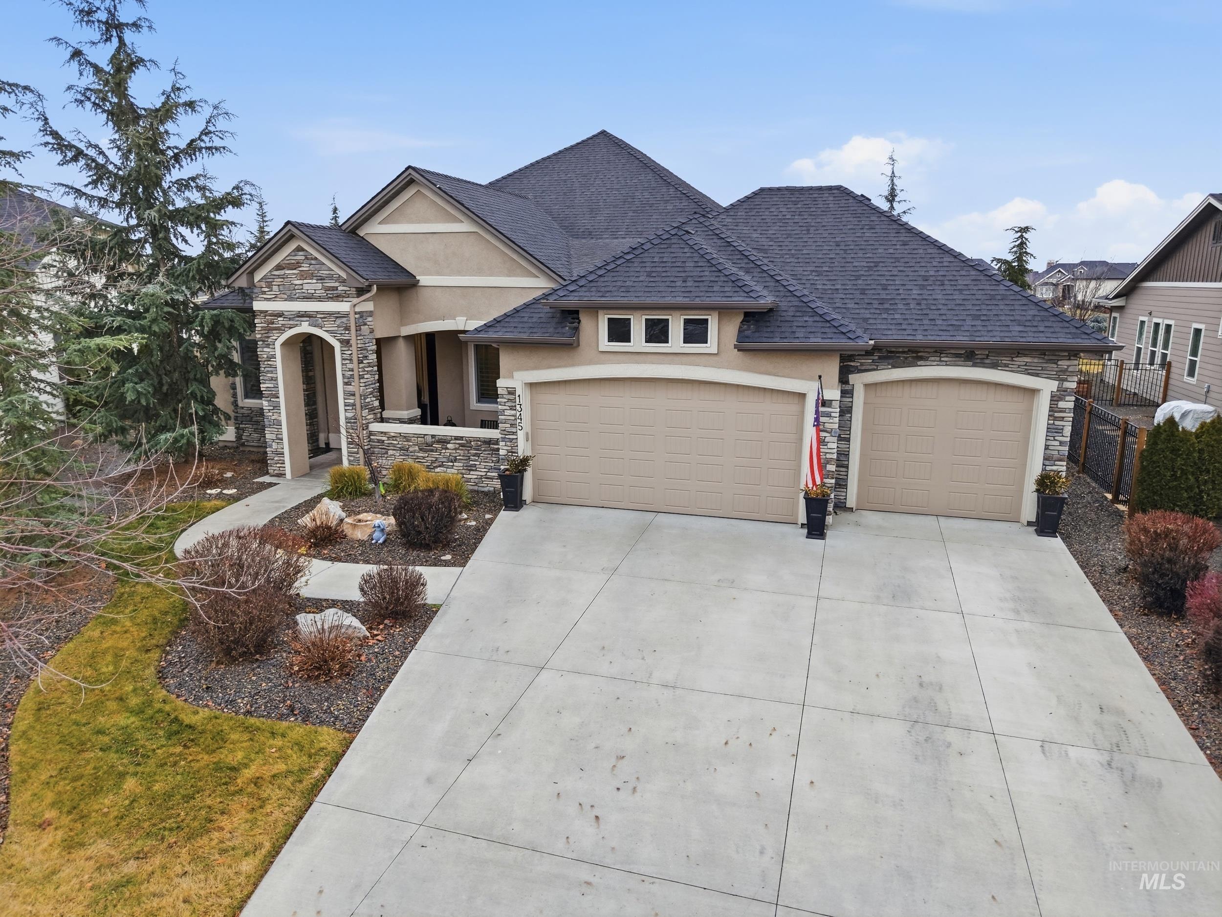 French country style house with stucco siding, stone siding, driveway, and a garage