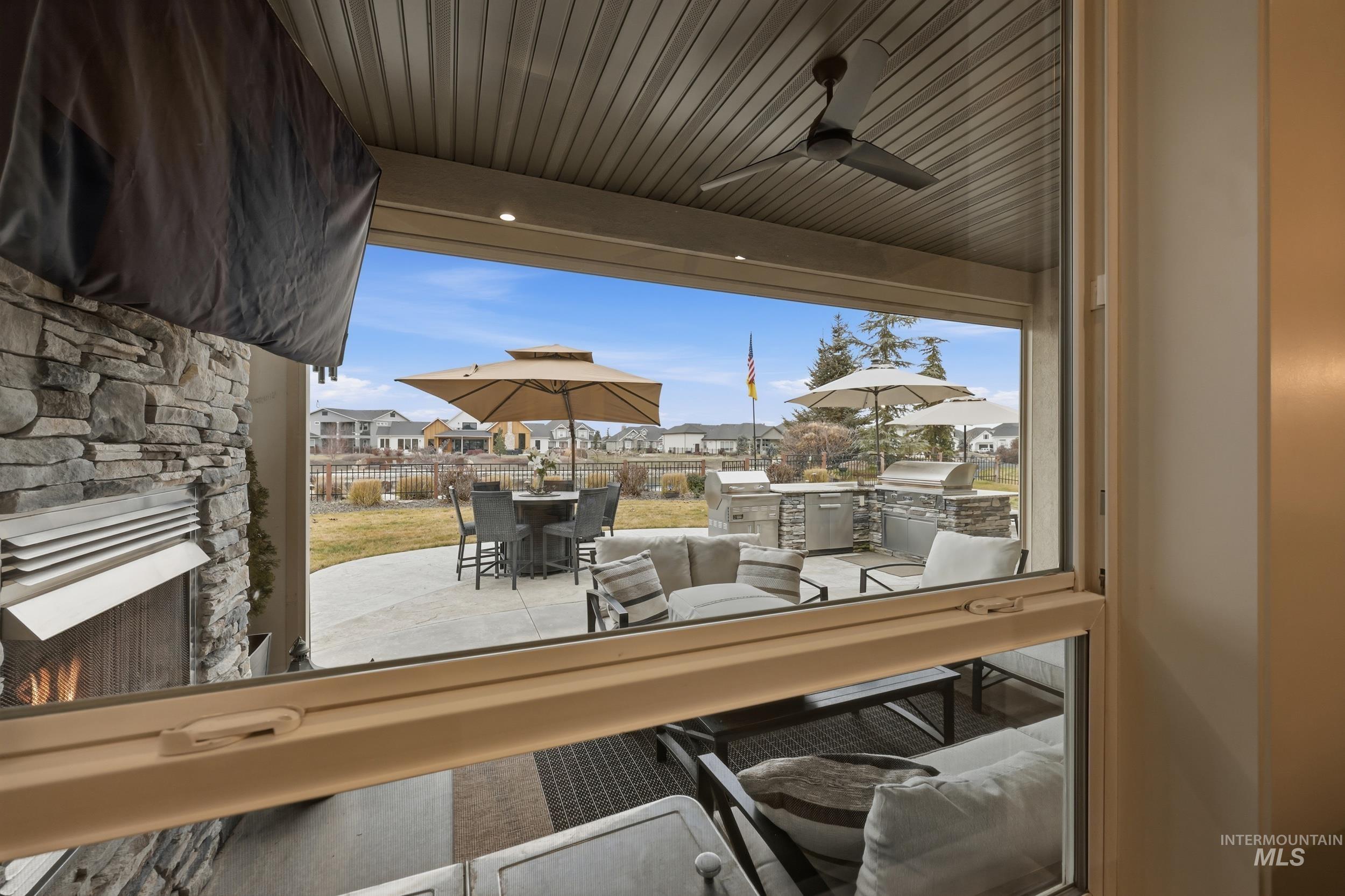 Detailed view of an outdoor stone fireplace, a residential view, a sunroom, and a ceiling fan
