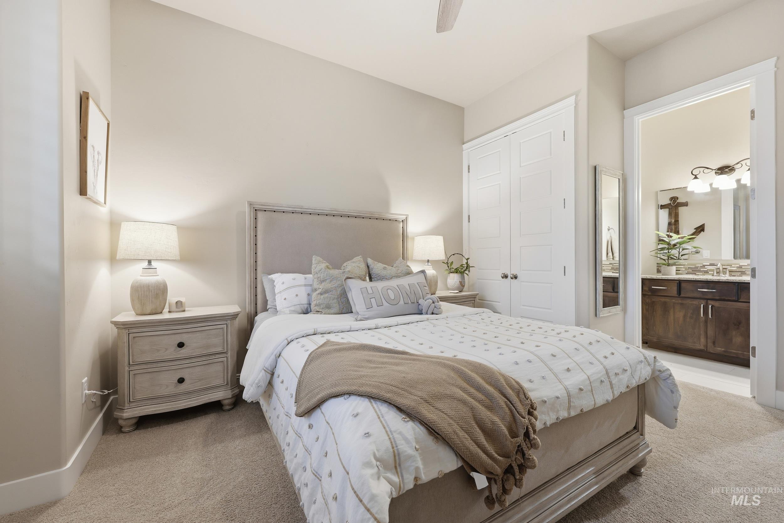 Bedroom featuring light colored carpet, a ceiling fan, a closet, and connected bathroom