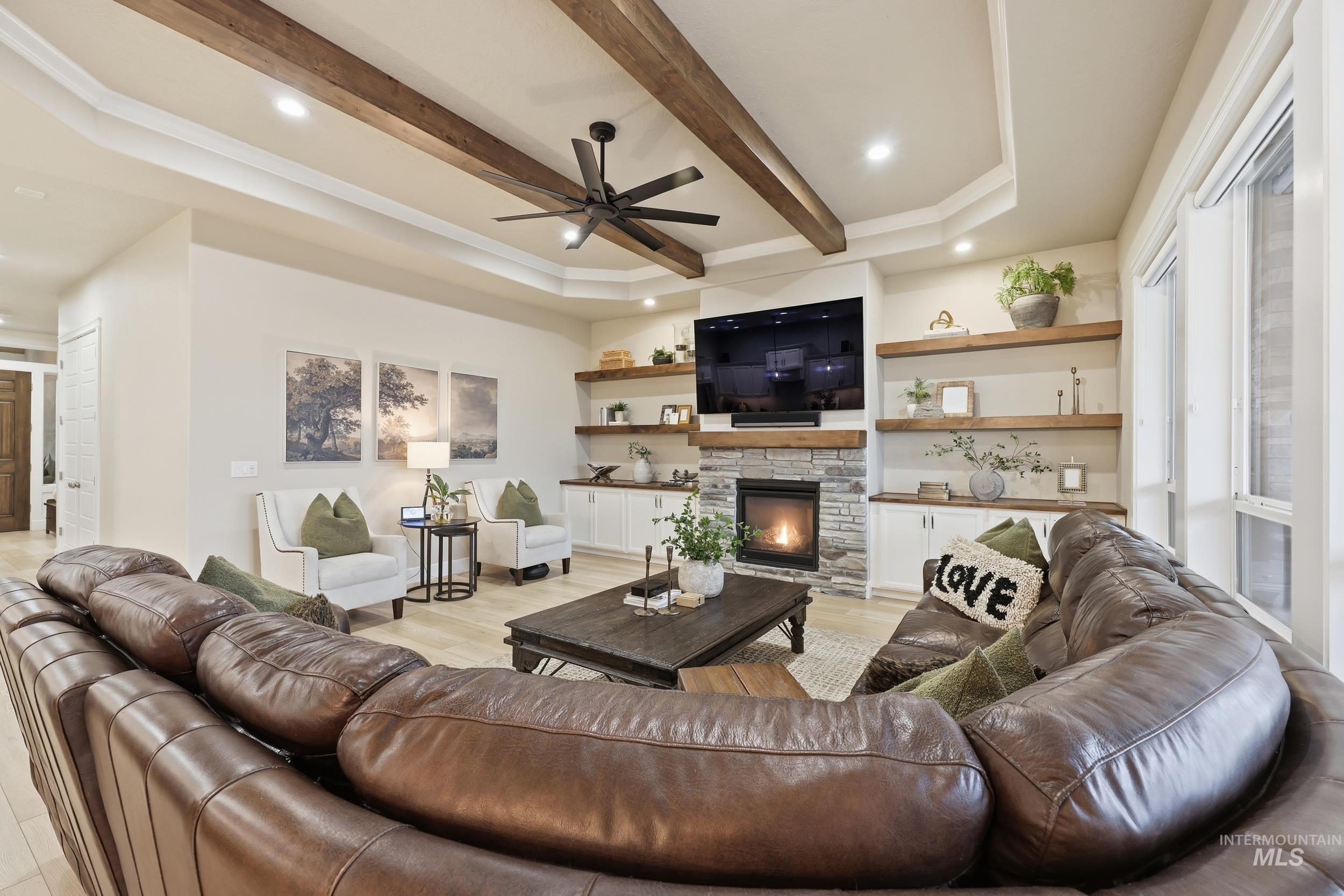 Living area featuring a ceiling fan, beam ceiling, recessed lighting, a stone fireplace, and light wood-style floors