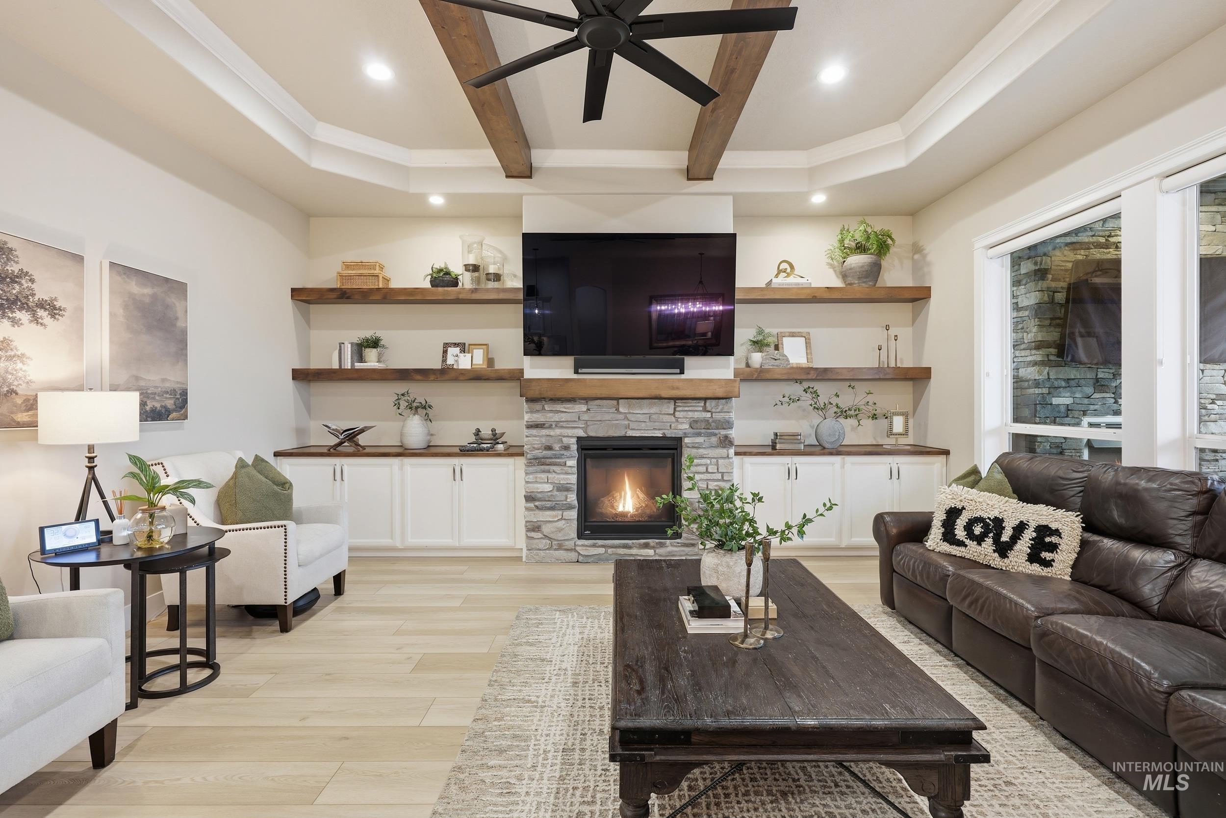Living room with beamed ceiling, light wood finished floors, a fireplace, a ceiling fan, and recessed lighting